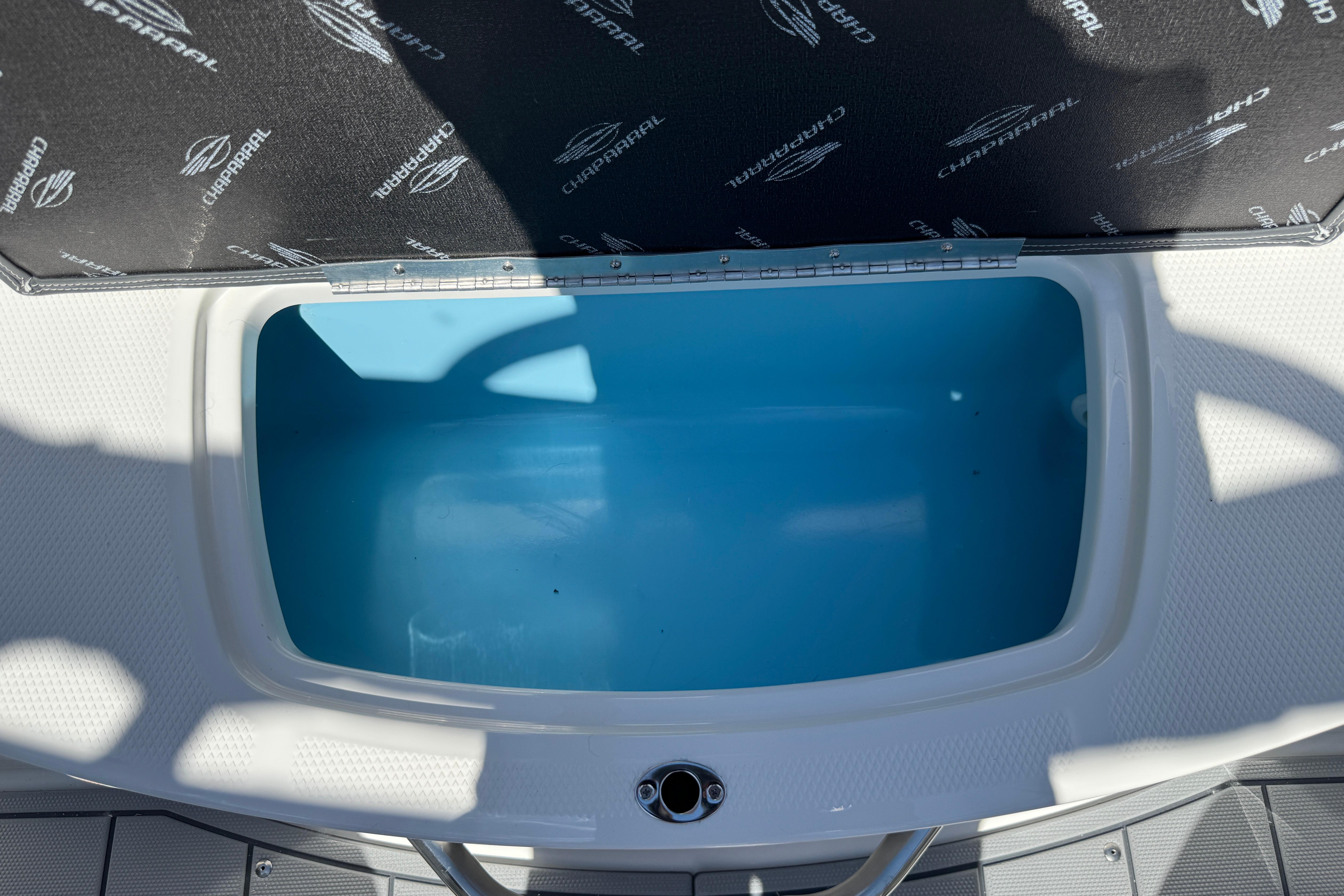 Open storage compartment on 2026 Chaparral 21 SSi boat, featuring a blue interior.