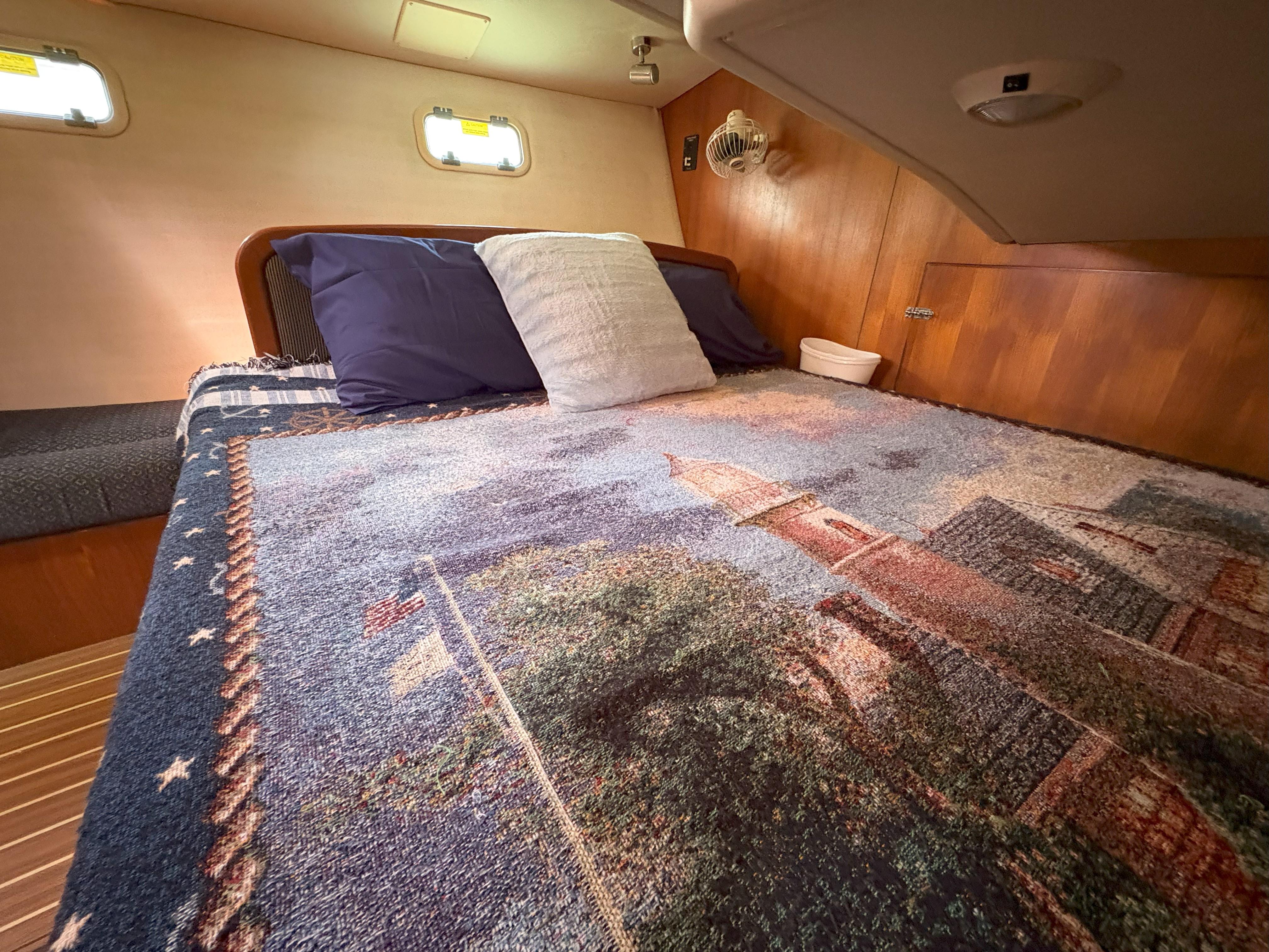 Cozy cabin interior of 2005 Hunter 38 sailboat with decorative bedding and wooden accents.