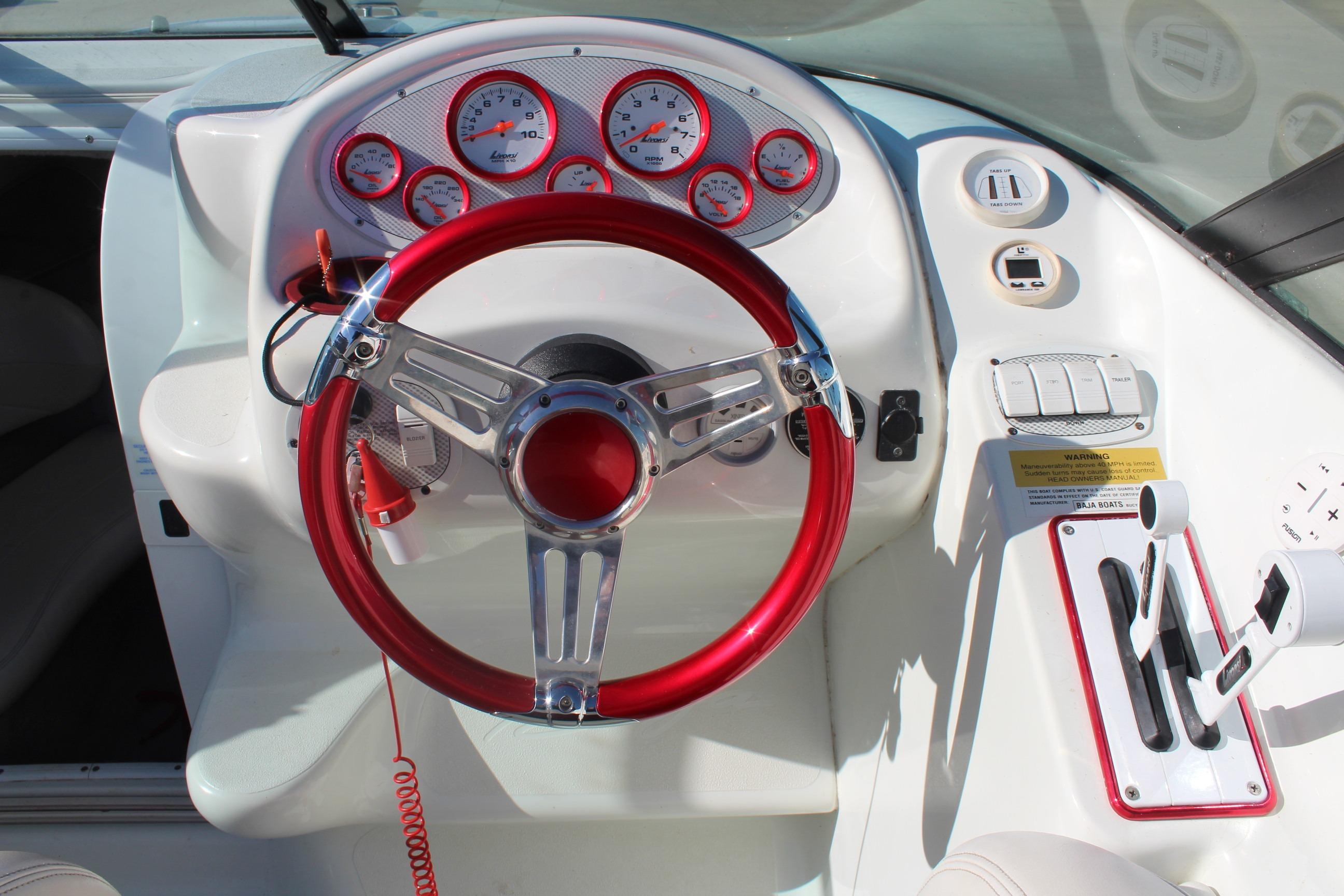 1996 Baja 232 boat dashboard with red steering wheel and gauges.