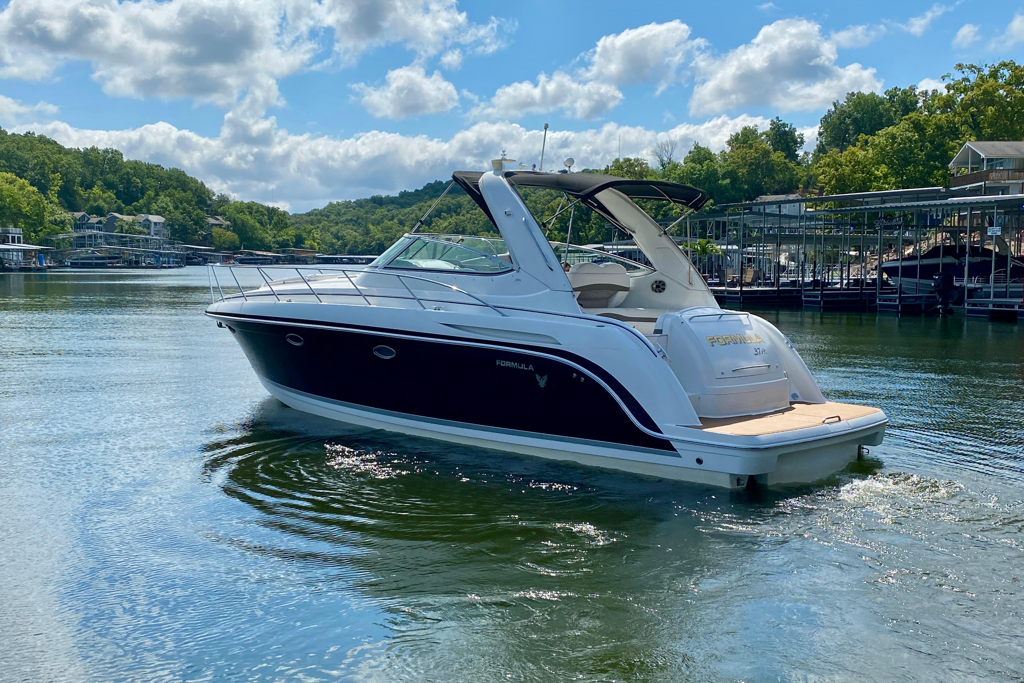 2004 Formula 37 PC yacht cruising on a sunny lake with lush green surroundings.