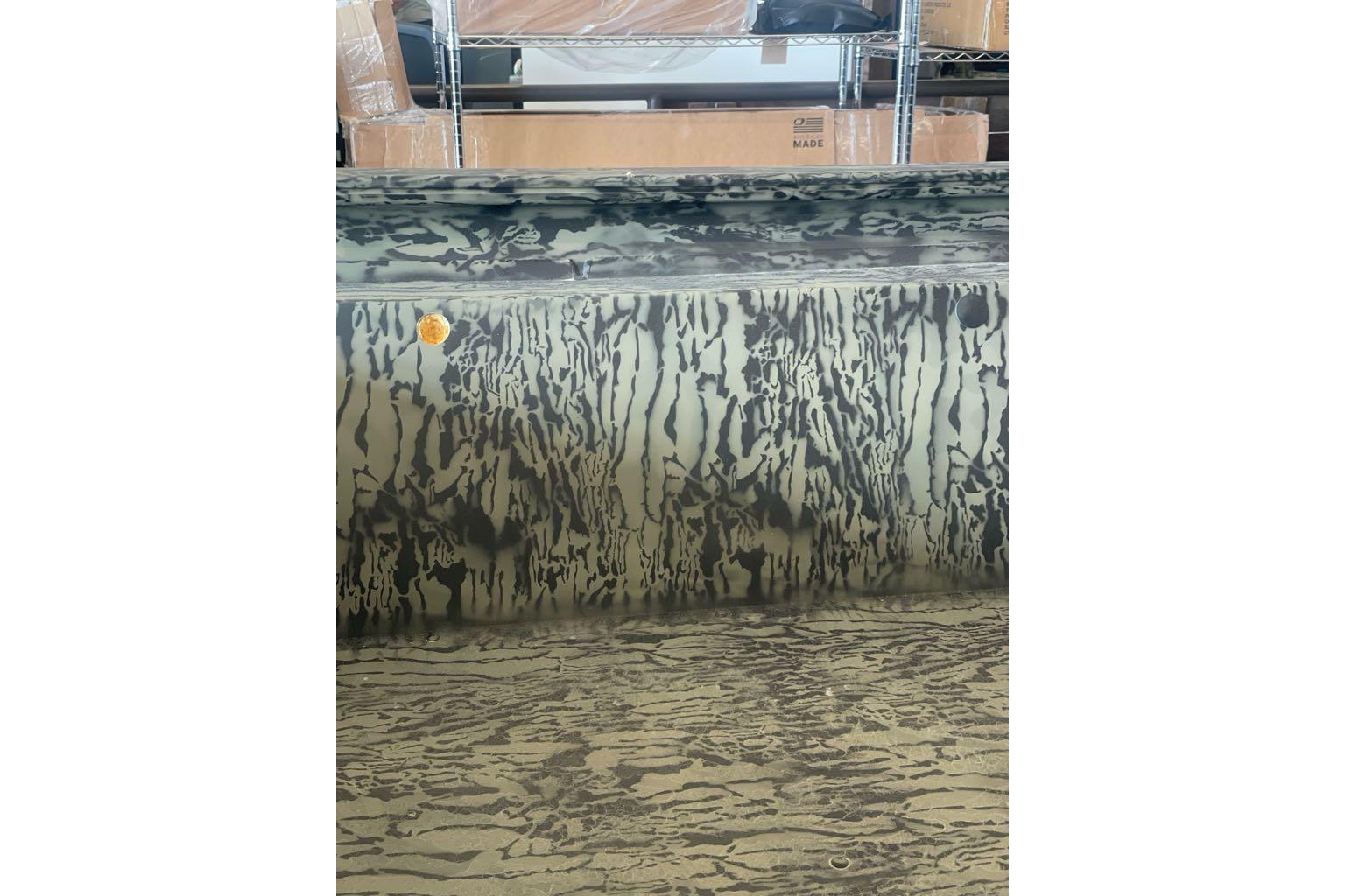 2025 Tracker Grizzly 1860 Utility boat with camouflage pattern in a warehouse setting.