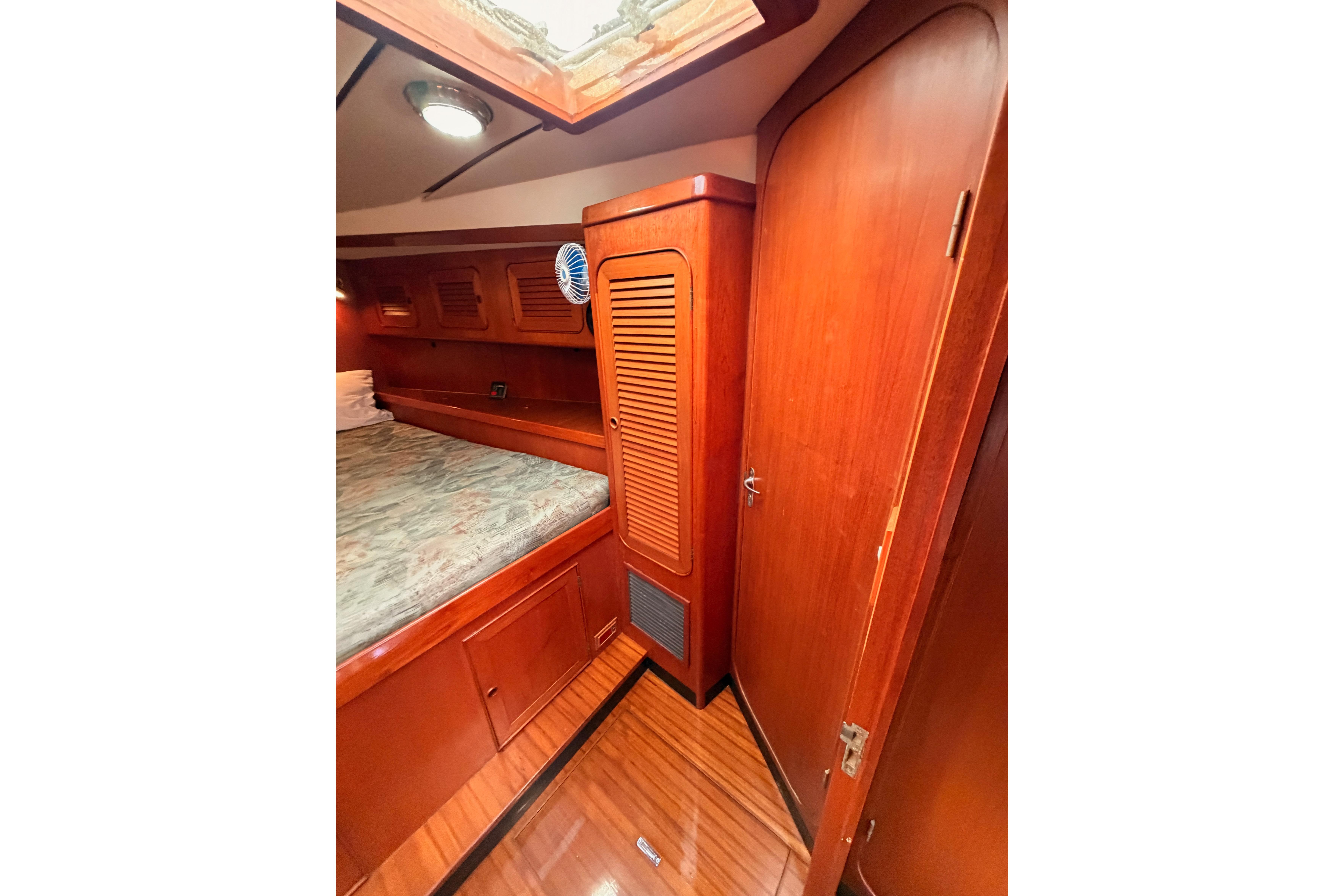 Interior cabin of 1991 Hylas 51 yacht with wooden finishes and cozy bed.