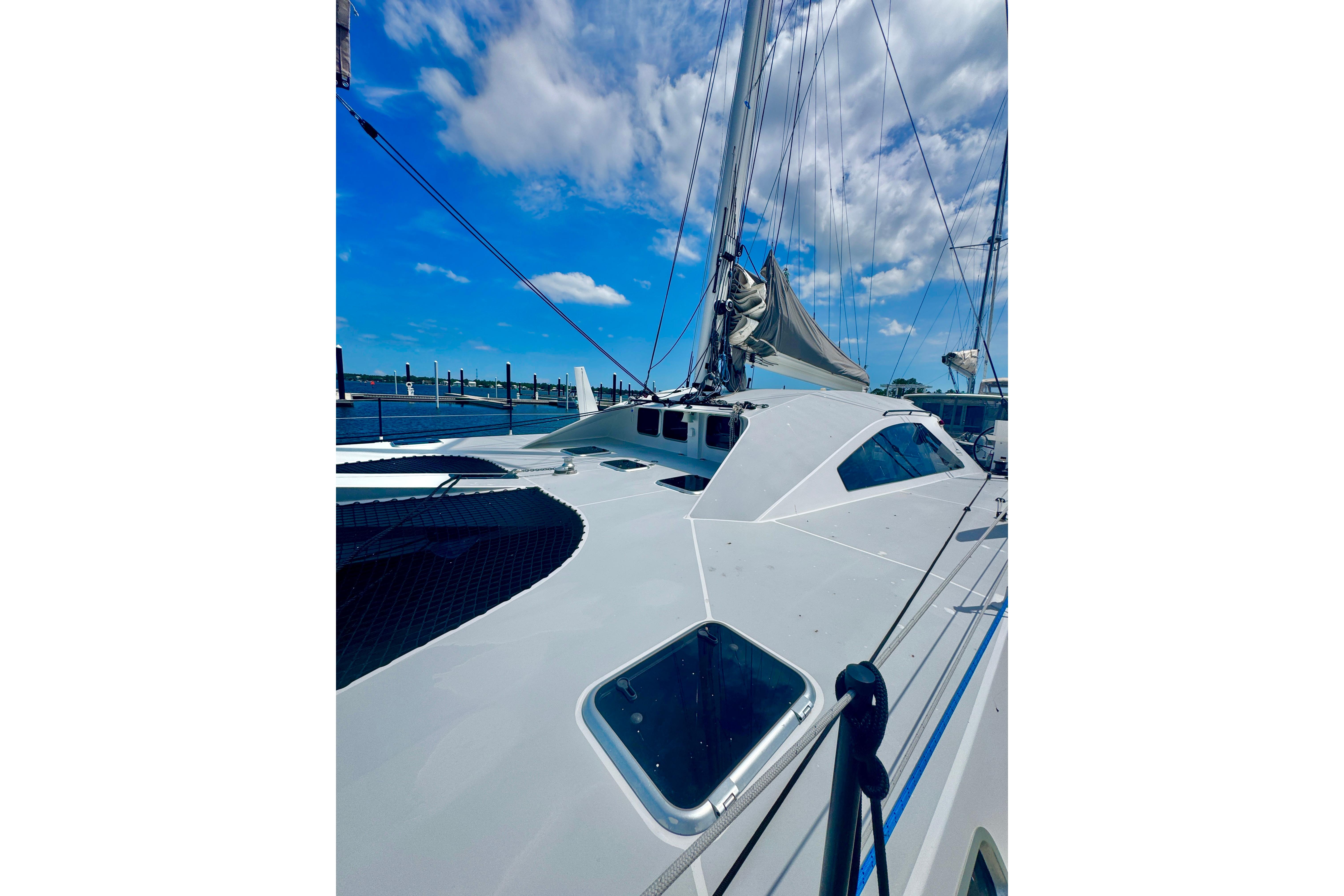 2023 Schionning Arrow 1280S catamaran docked under a bright blue sky.