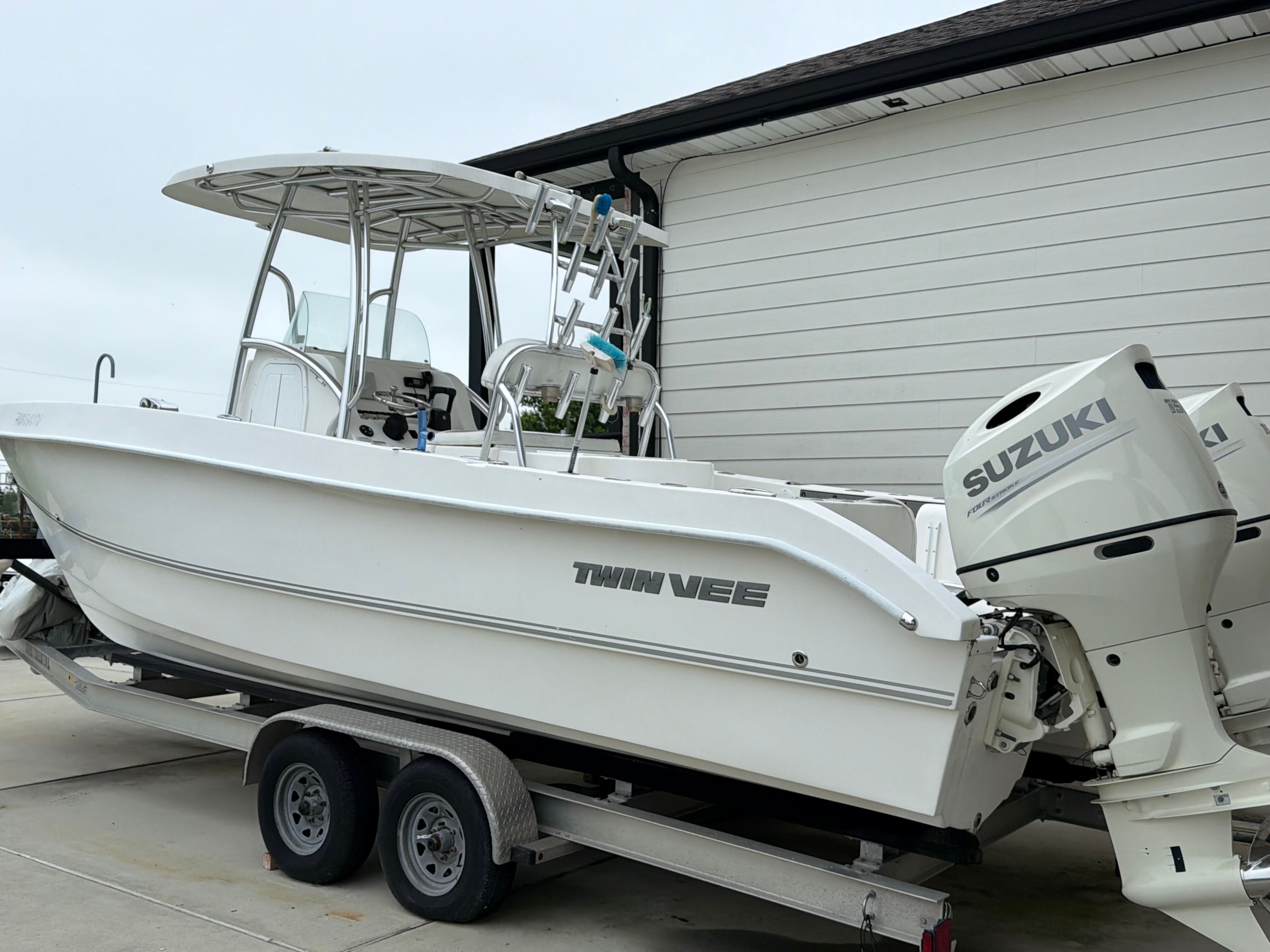 A white Twin Vee Ocean Cat boat on a trailer, featuring Suzuki engines.