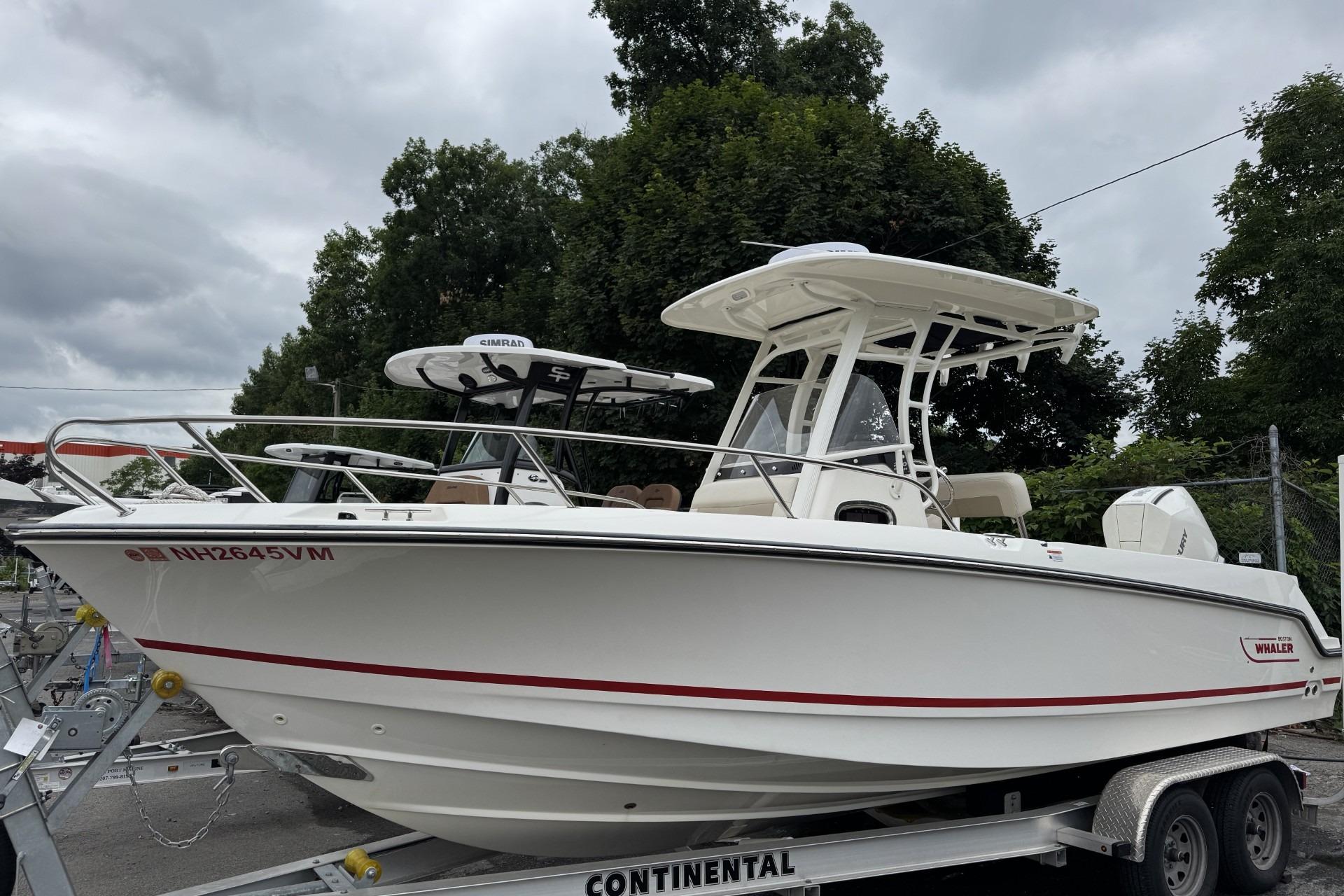 2024 Boston Whaler 230 Outrage boat on trailer, parked outdoors under cloudy sky.