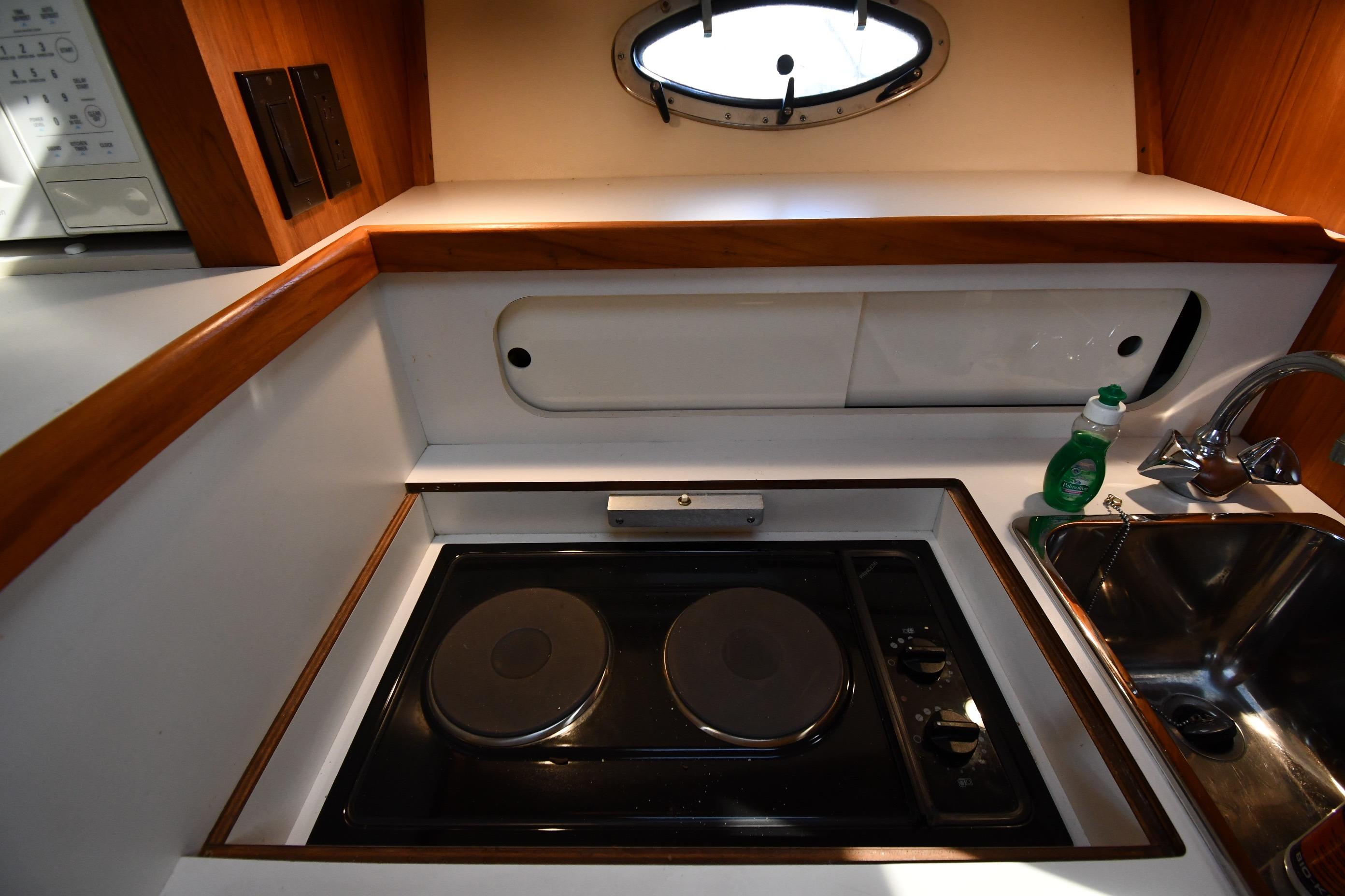1998 Tiara Yachts 3100 Open galley with stove, sink, and porthole window.