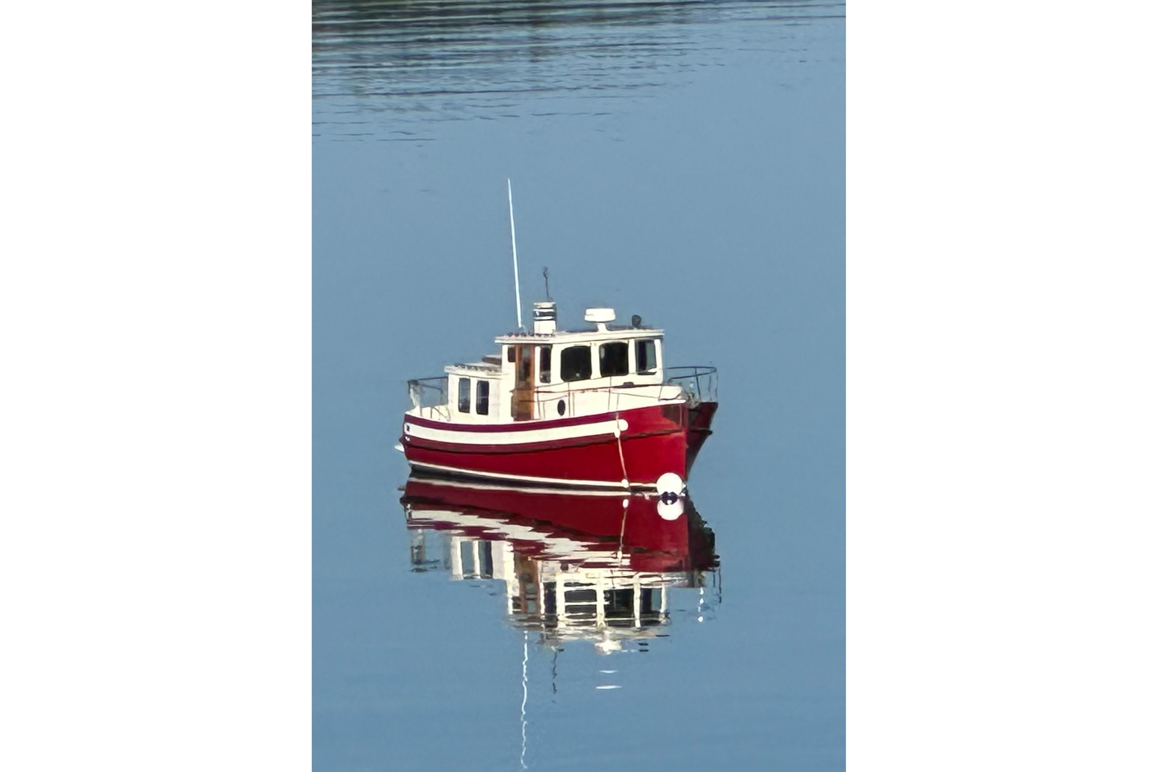 Red 1985 Nordic Tug 26 boat reflecting on calm water.