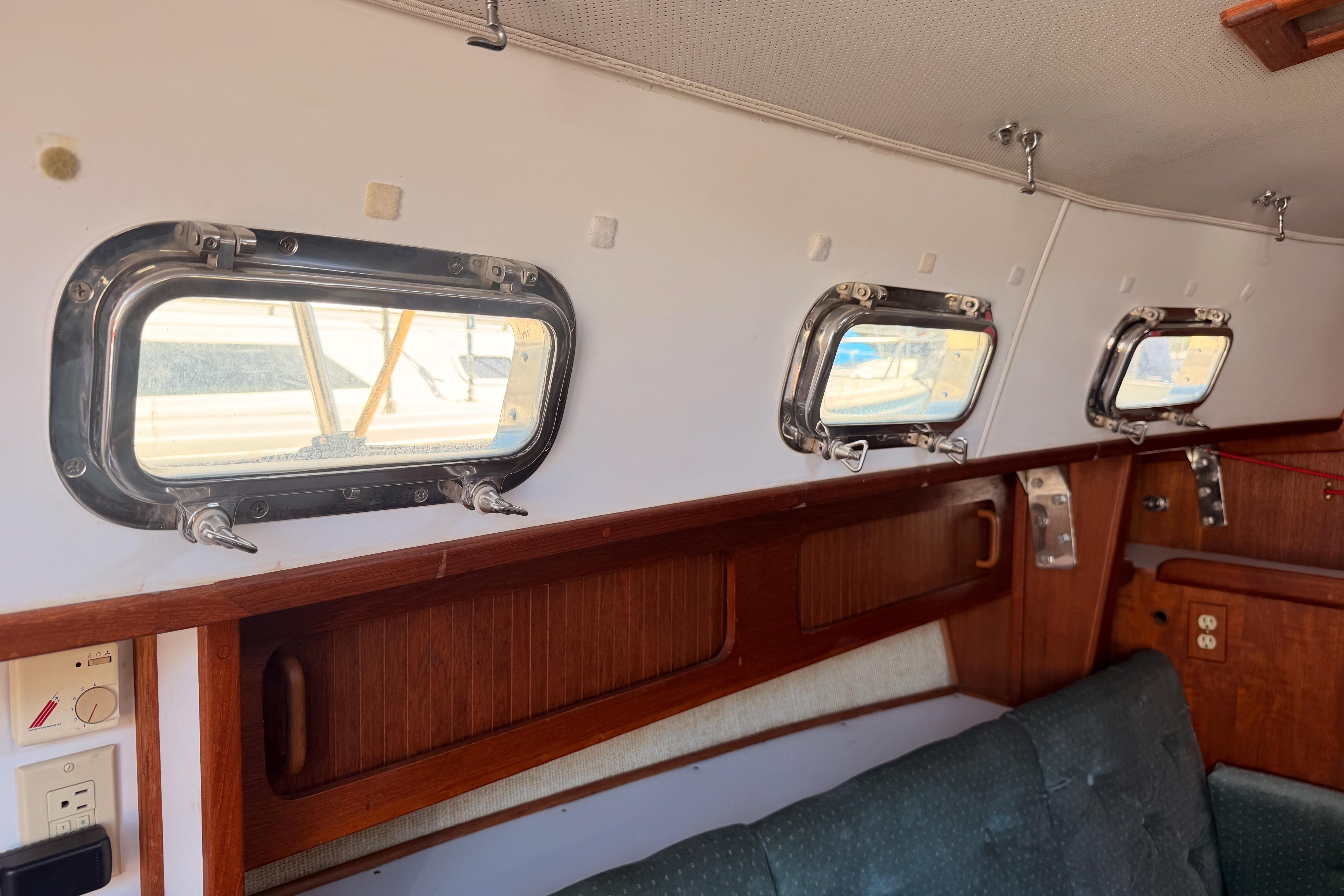 Interior of 1991 Caliber 33 sailboat with portholes and wooden cabinetry.