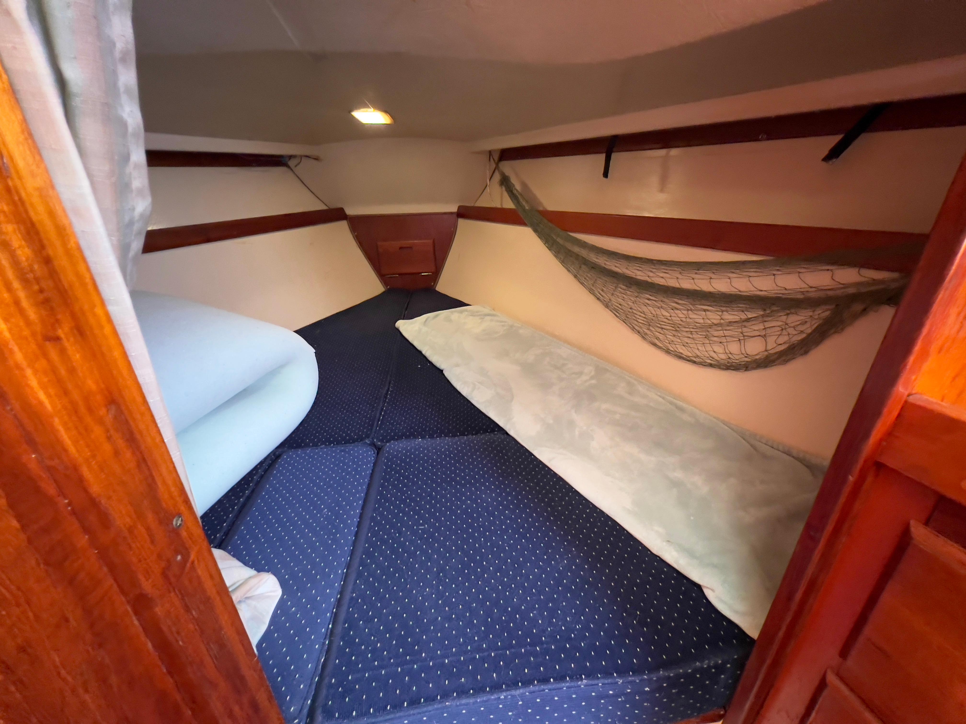 Cozy cabin interior of a 1986 Catalina 30 sailboat with blue cushions and wooden accents.