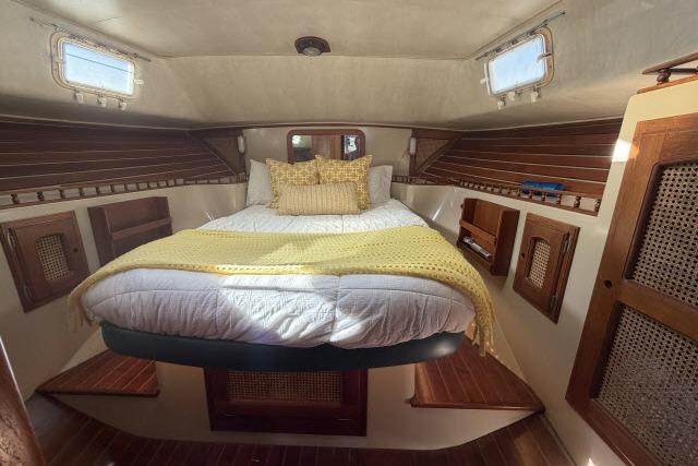 Cozy cabin interior of 1982 Lancer 45 Motorsailer with bed and wooden accents.