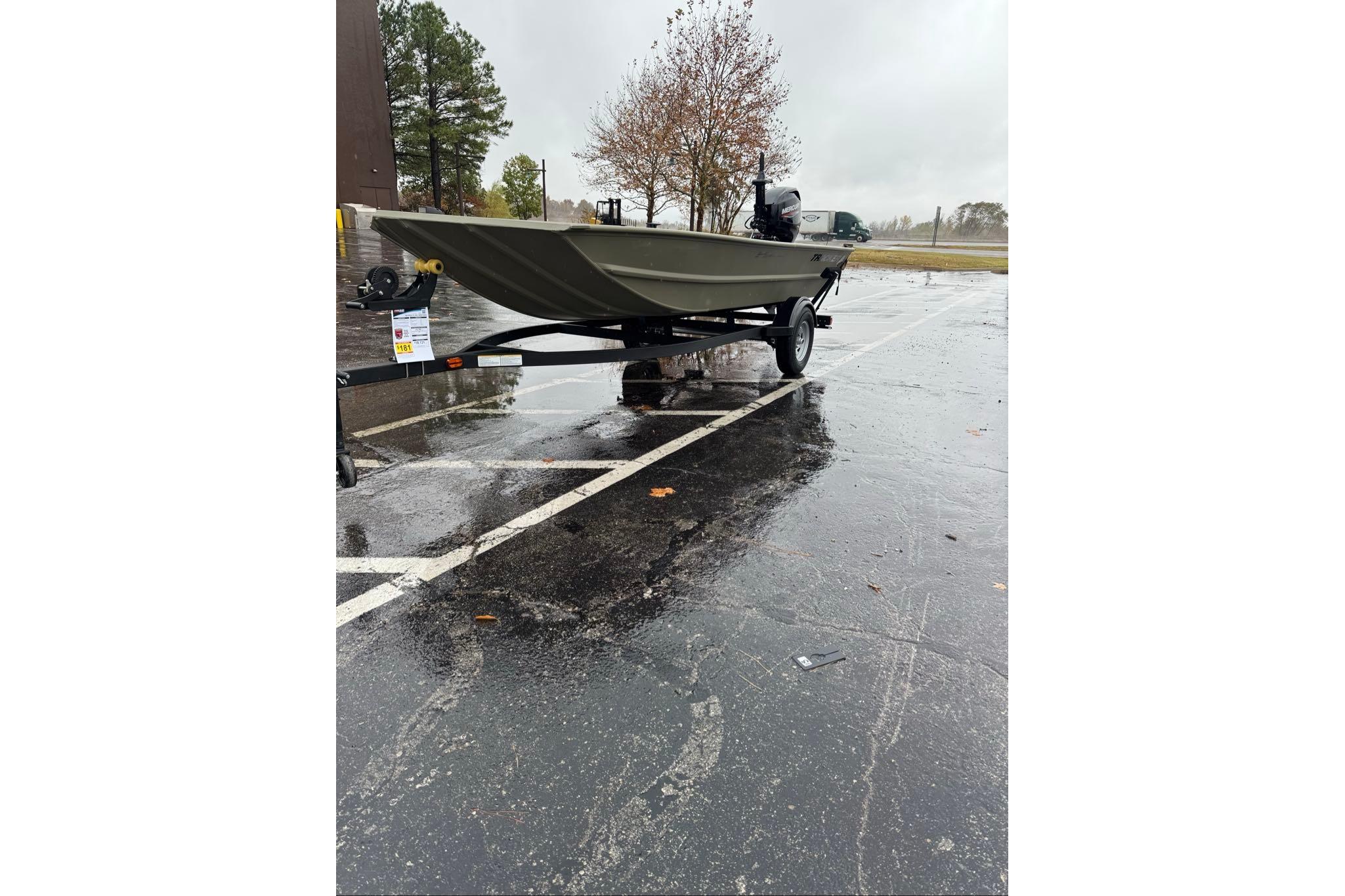 2026 Tracker Grizzly 1654 T Sportsman boat on trailer in rainy parking lot.