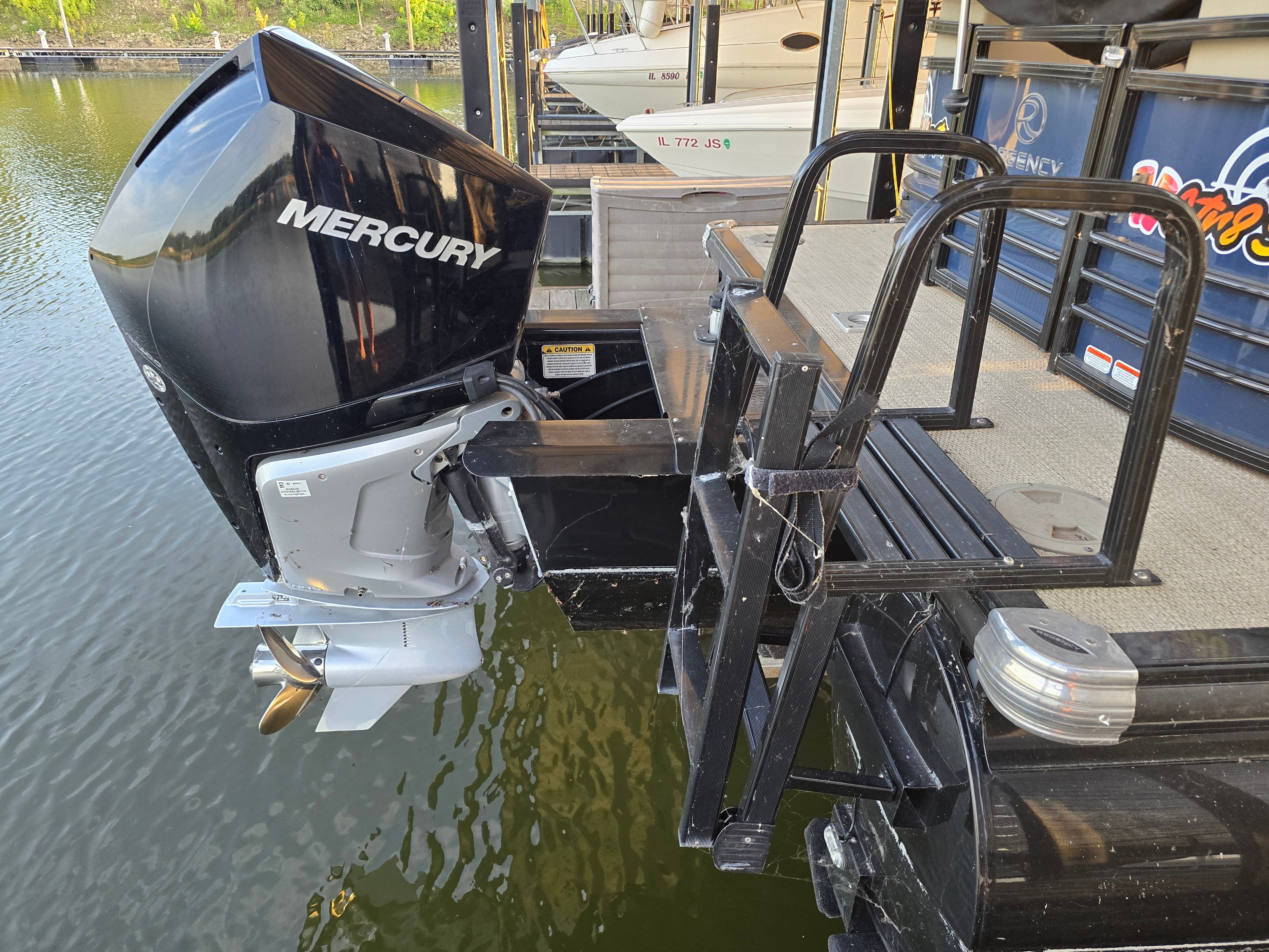 A 2021 Regency 230 LE3 with a Mercury outboard motor, docked at a pier.