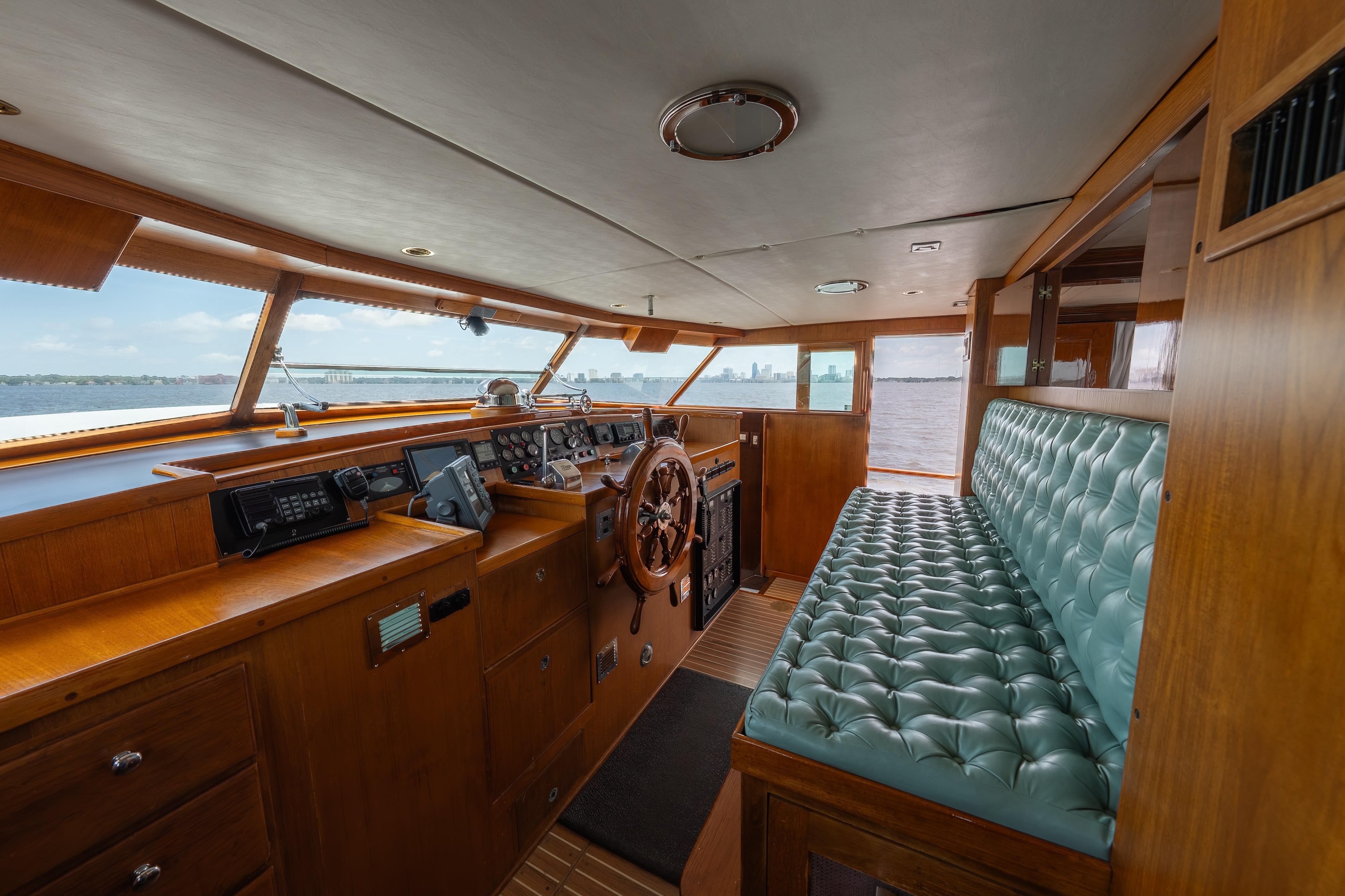 1963 Trumpy Classic yacht interior with vintage helm, turquoise seating, and panoramic windows.