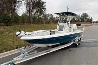 2026 Mako 24 APEX boat on trailer, parked on road near grassy area.