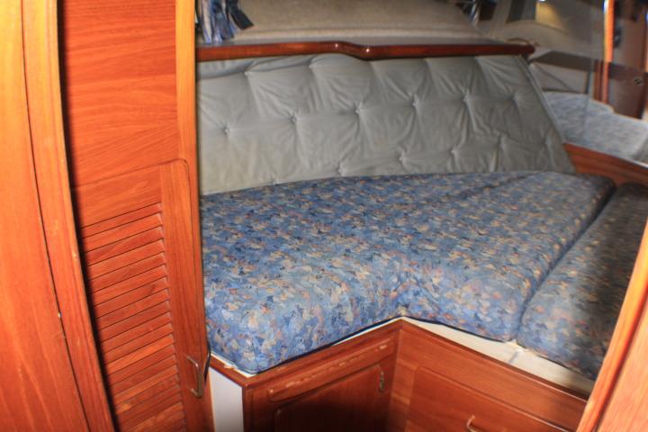 1988 Tollycraft 30 Sport Cruiser cabin with blue-patterned bedding and wooden cabinetry.