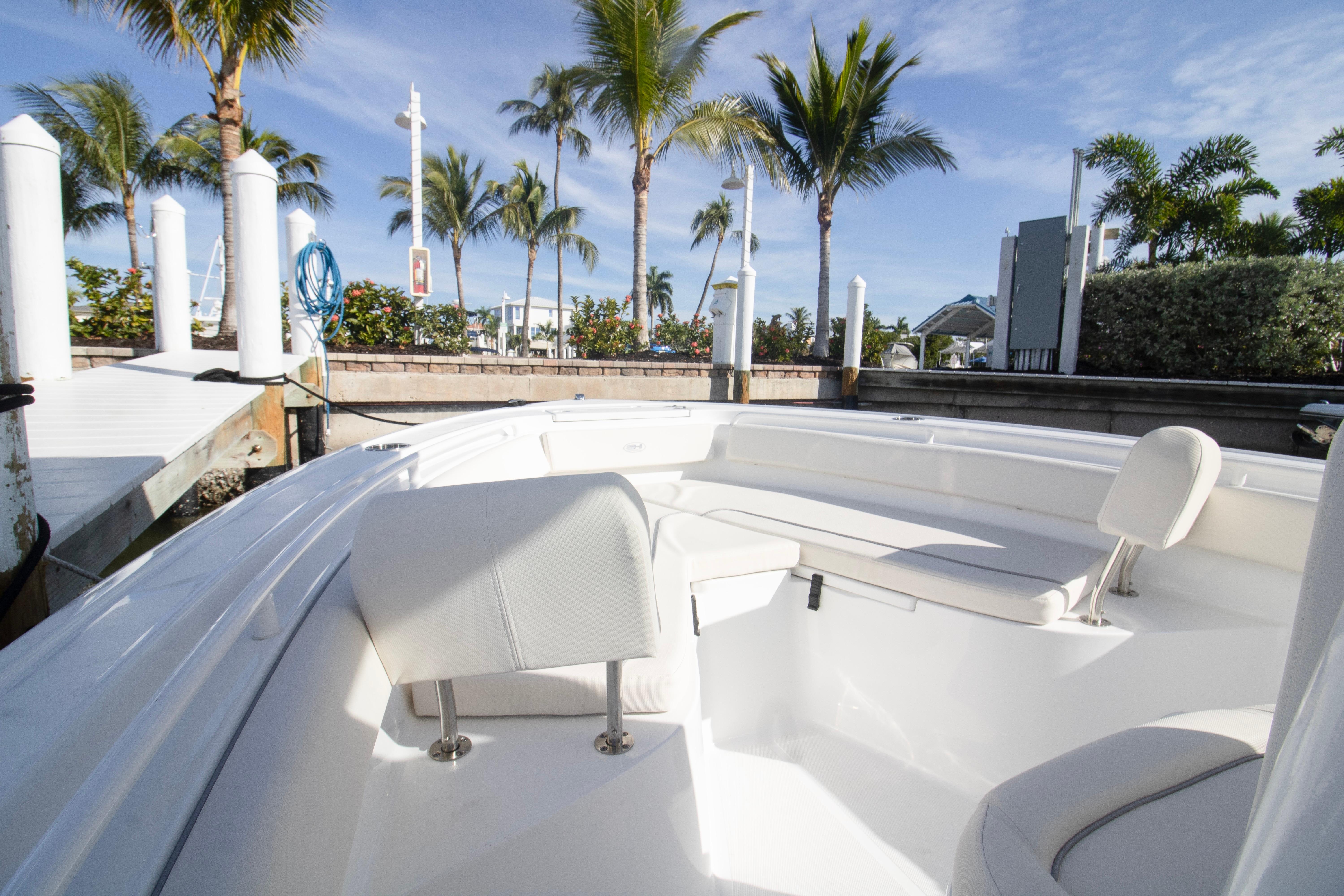 2026 Sea Hunt Ultra 245 SE boat interior with white seating, docked near palm trees.