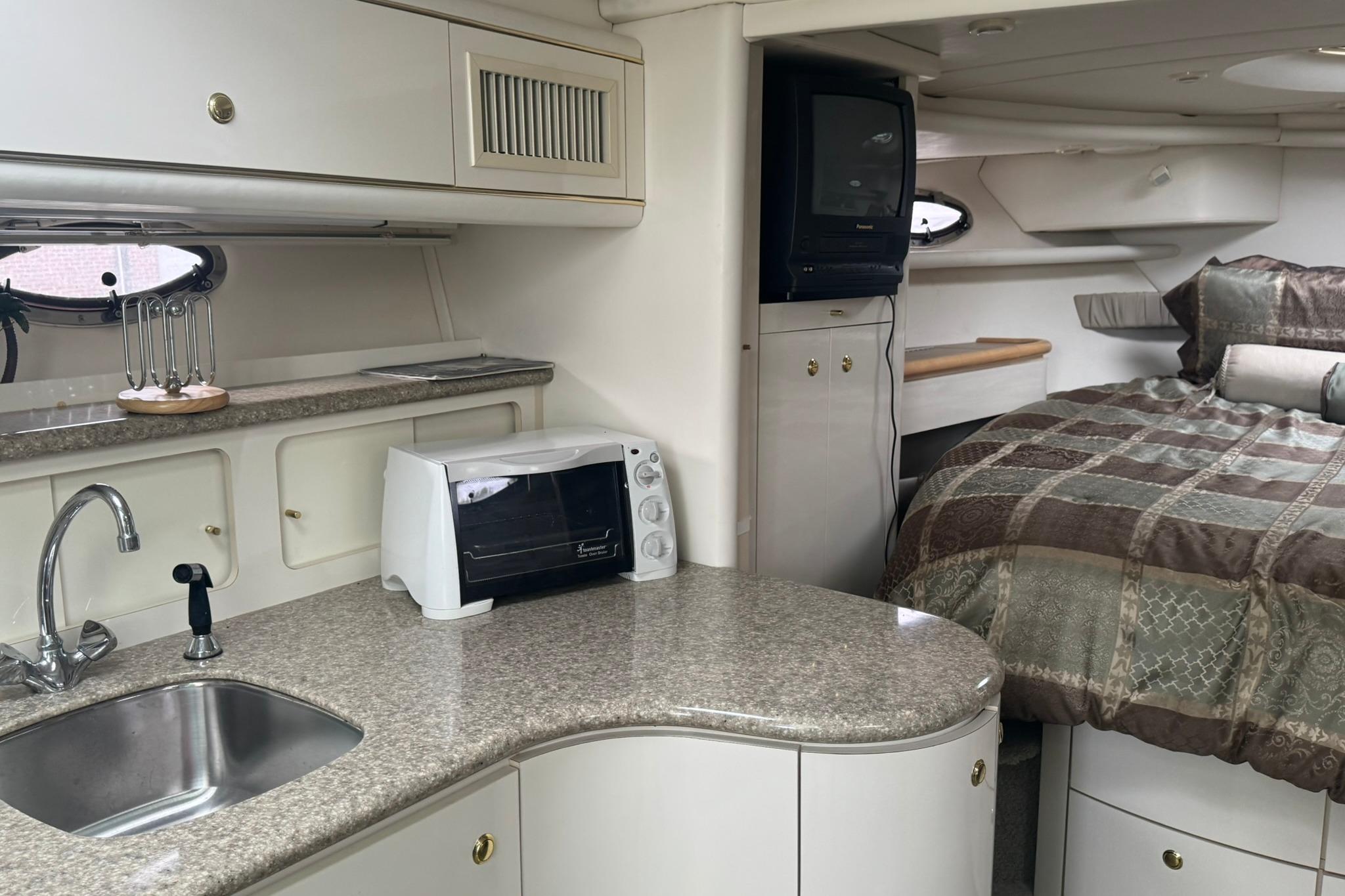 Interior of 1998 Maxum 3700 SCR yacht with kitchenette and cozy sleeping area.