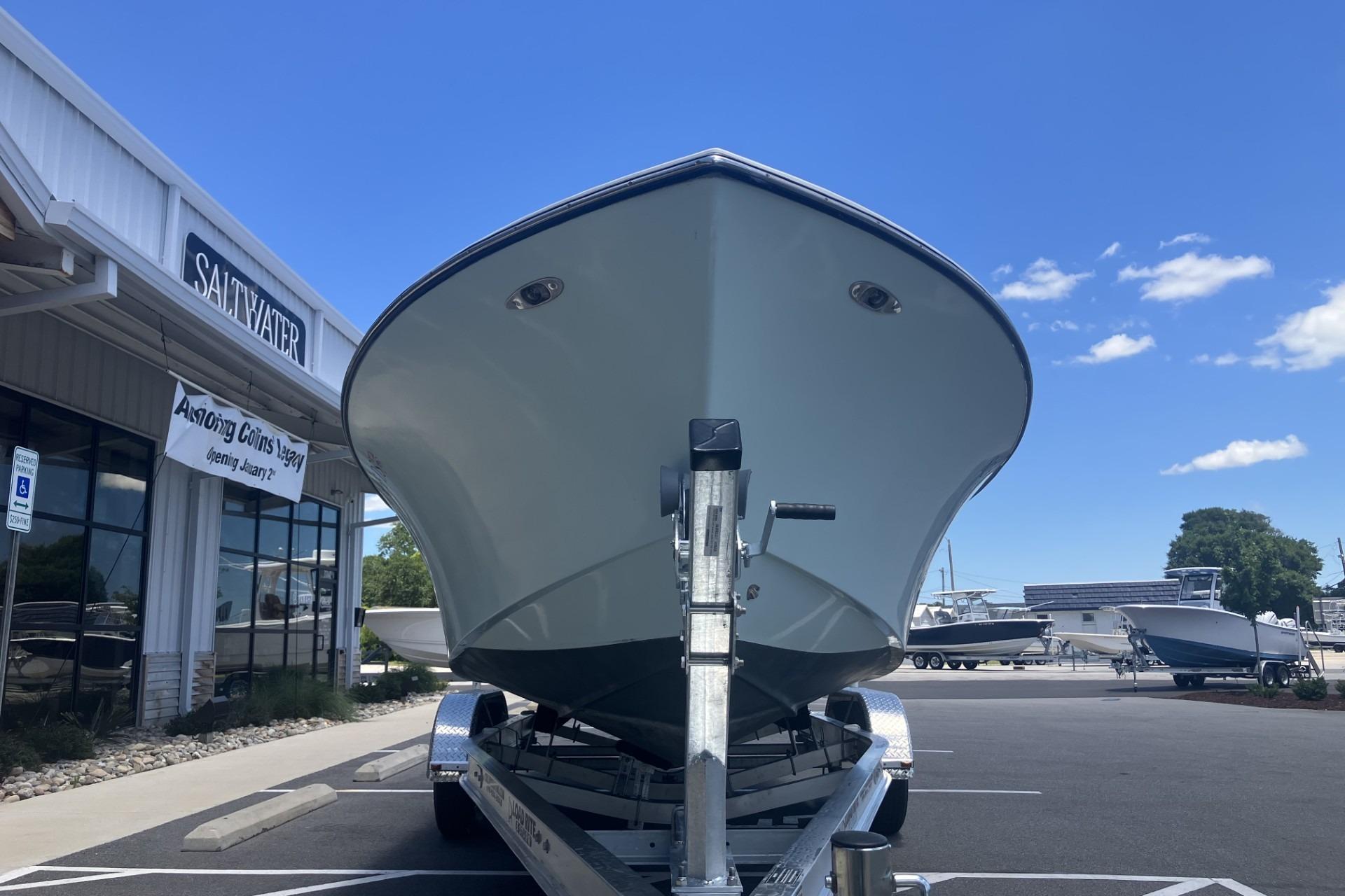 2022 May-Craft 2300 CCX boat on trailer at dealership under clear blue sky.