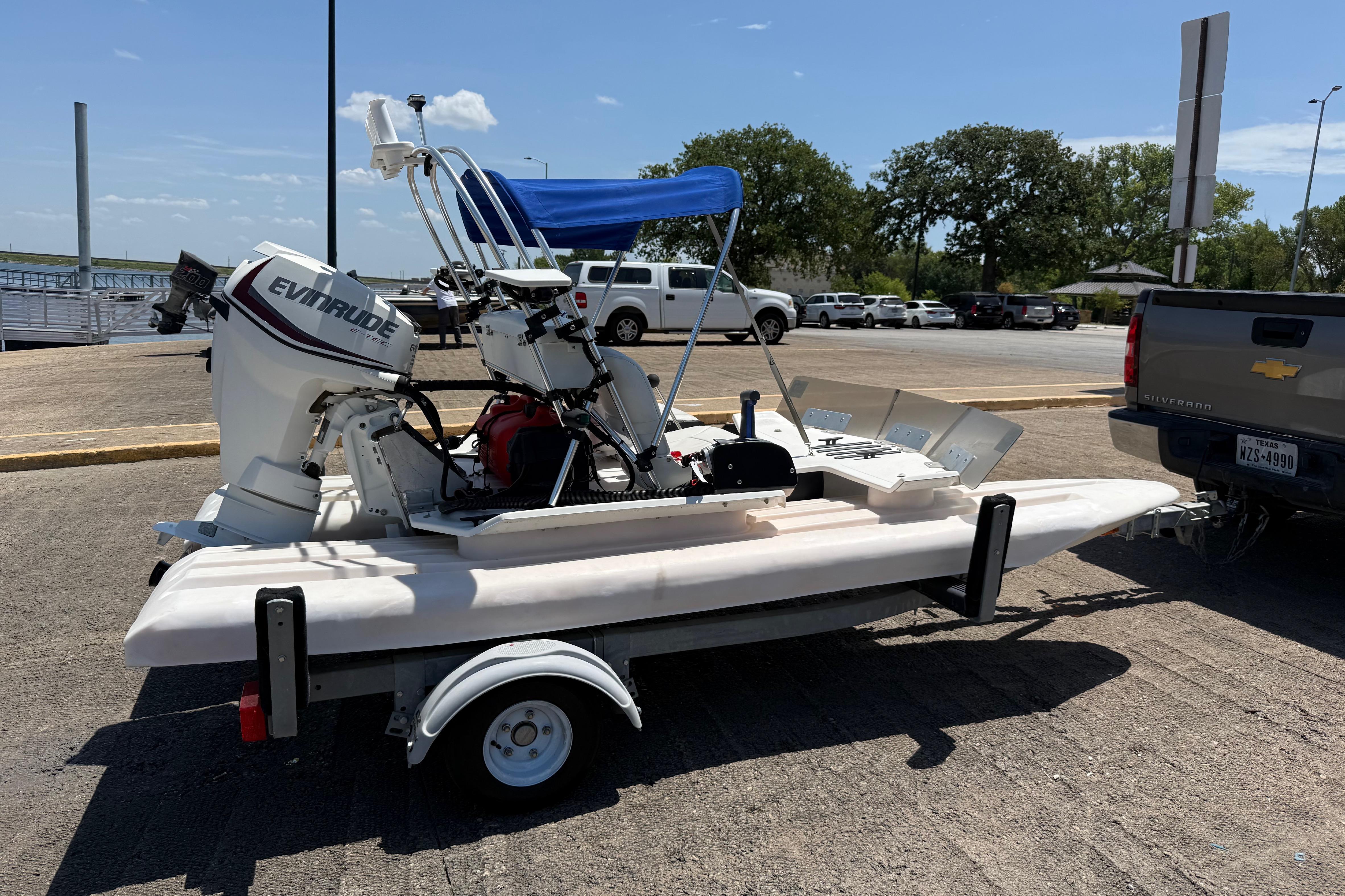 2016 CraigCat E2 Elite on trailer with Evinrude motor, parked near waterfront.