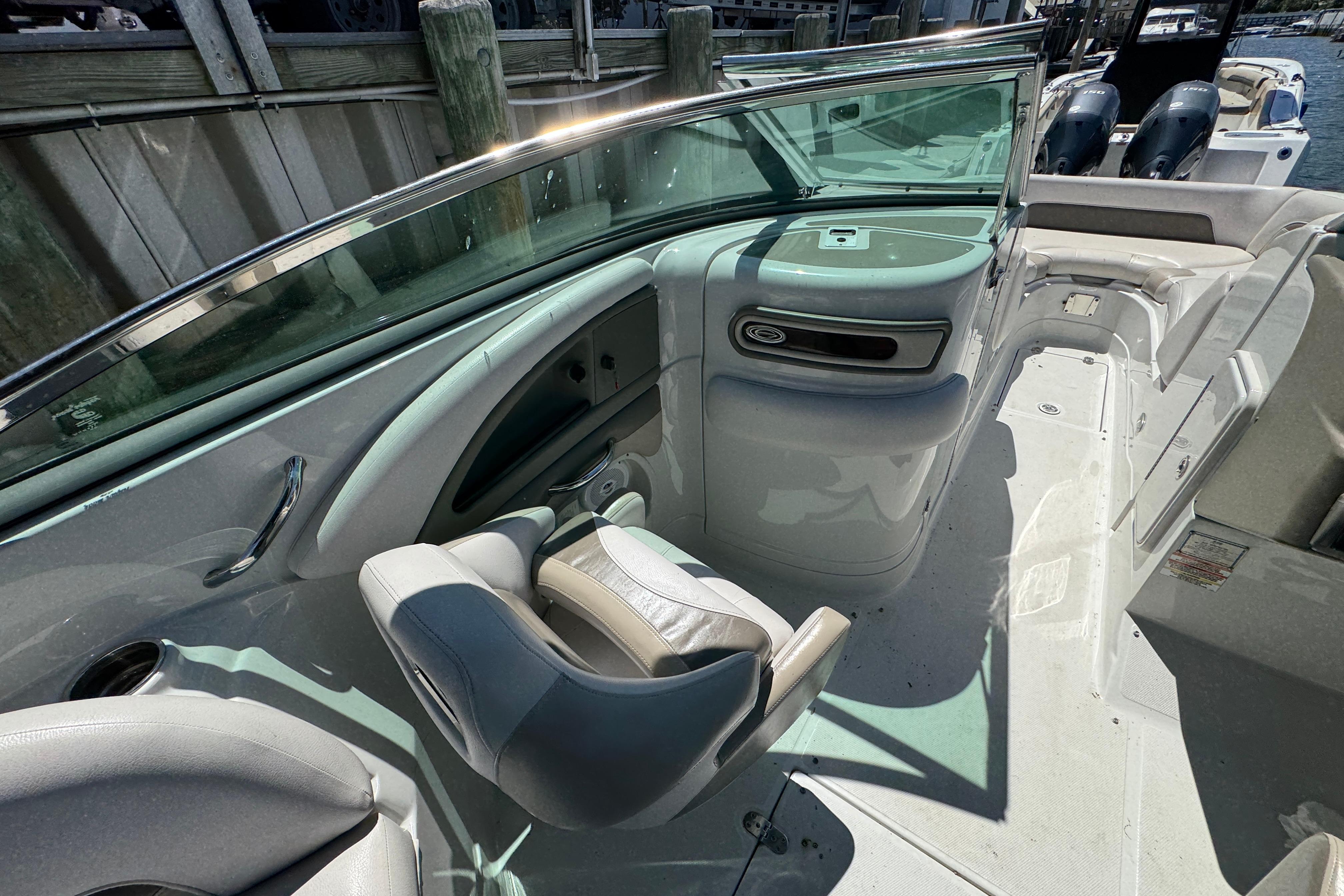 2013 Crownline Eclipse E6 XS boat interior with seating and helm, docked by wooden pier.