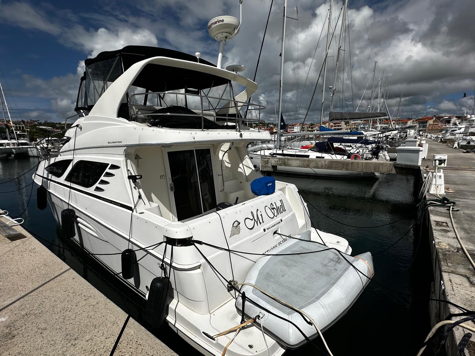 2006 Silverton 43 Sport Bridge yacht docked at a marina under cloudy skies.