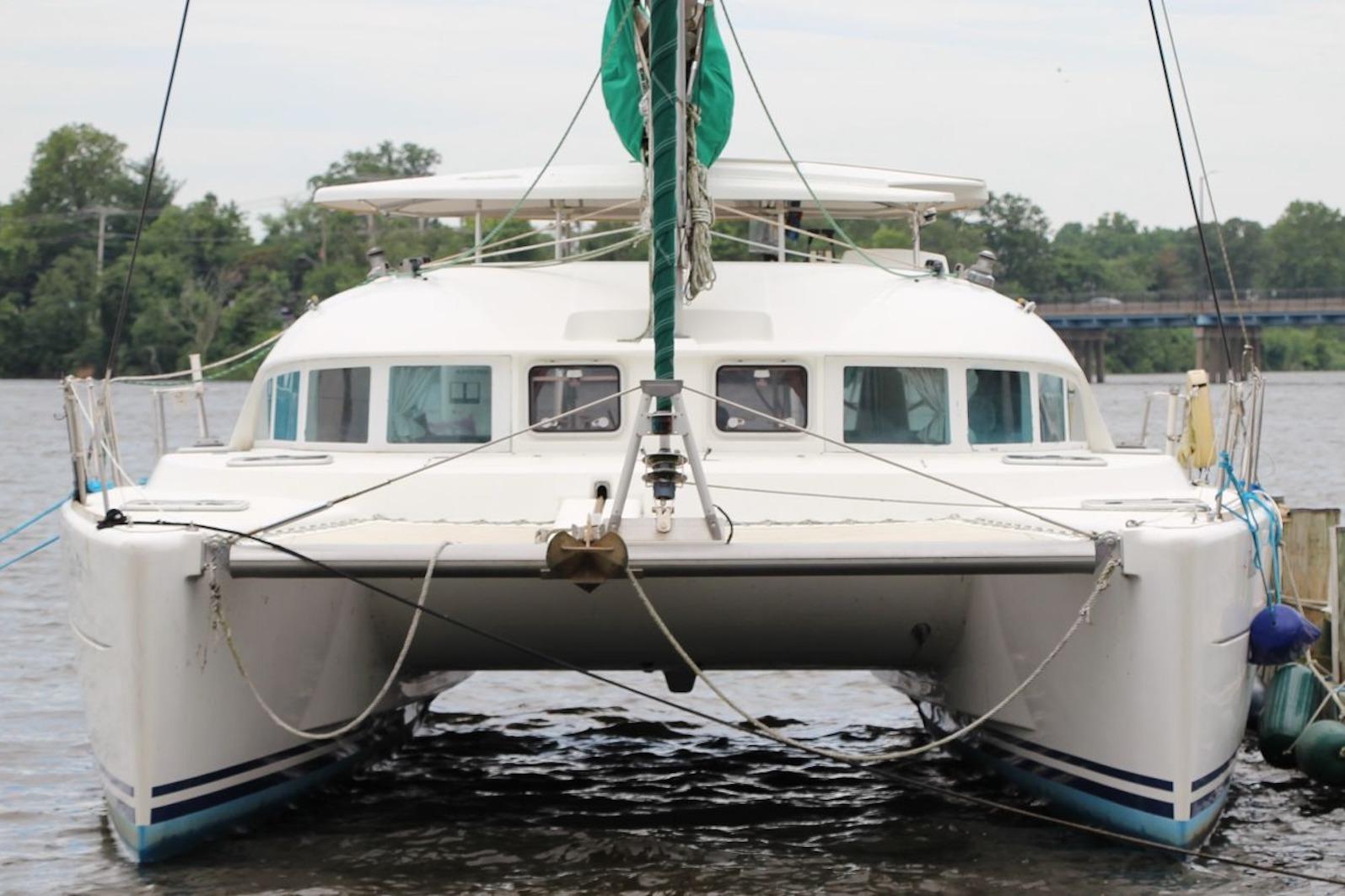 2004 Lagoon 380 catamaran docked on a calm river with lush greenery.