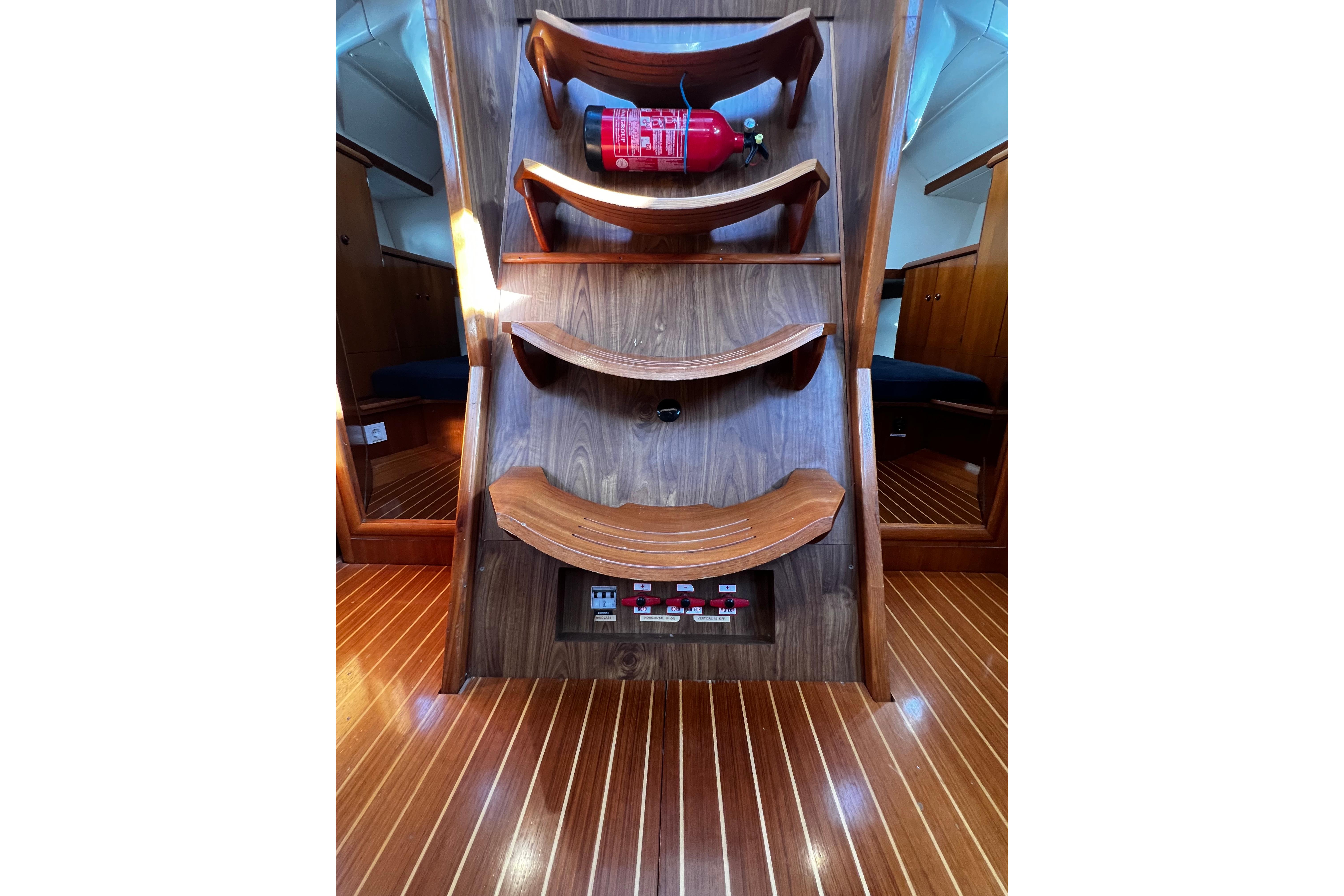 Interior of 1995 Jeanneau Sun Odyssey 45.1 yacht with wooden stairs and fire extinguisher.
