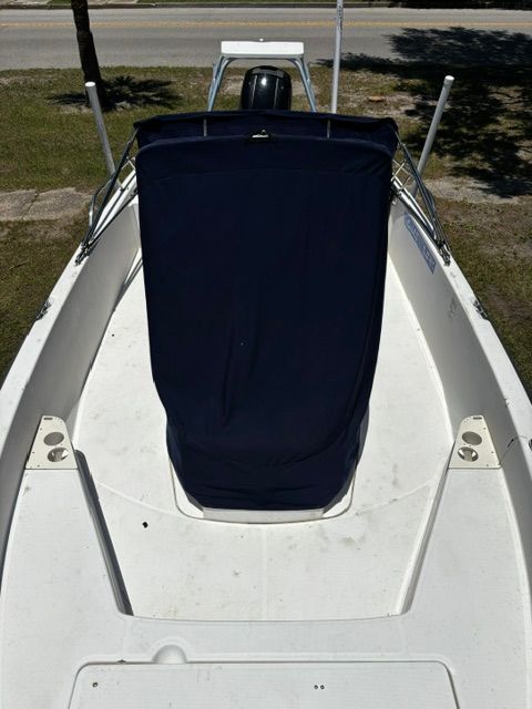 A 2008 Boston Whaler 200 Dauntless is on land. The boat has a cover.