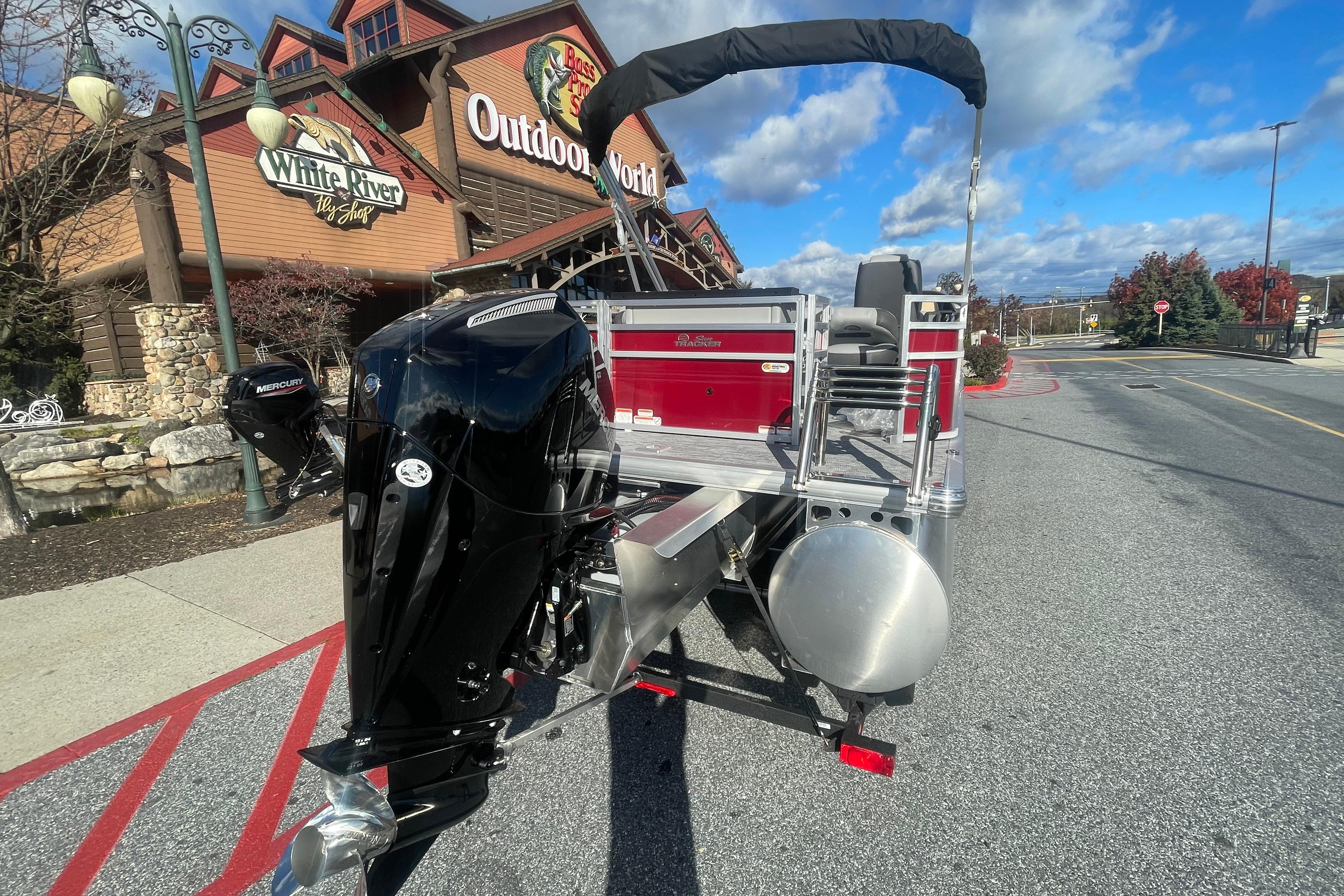 2026 Sun Tracker SportFish 22 XP3 boat outside Outdoor World store, featuring a Mercury engine.