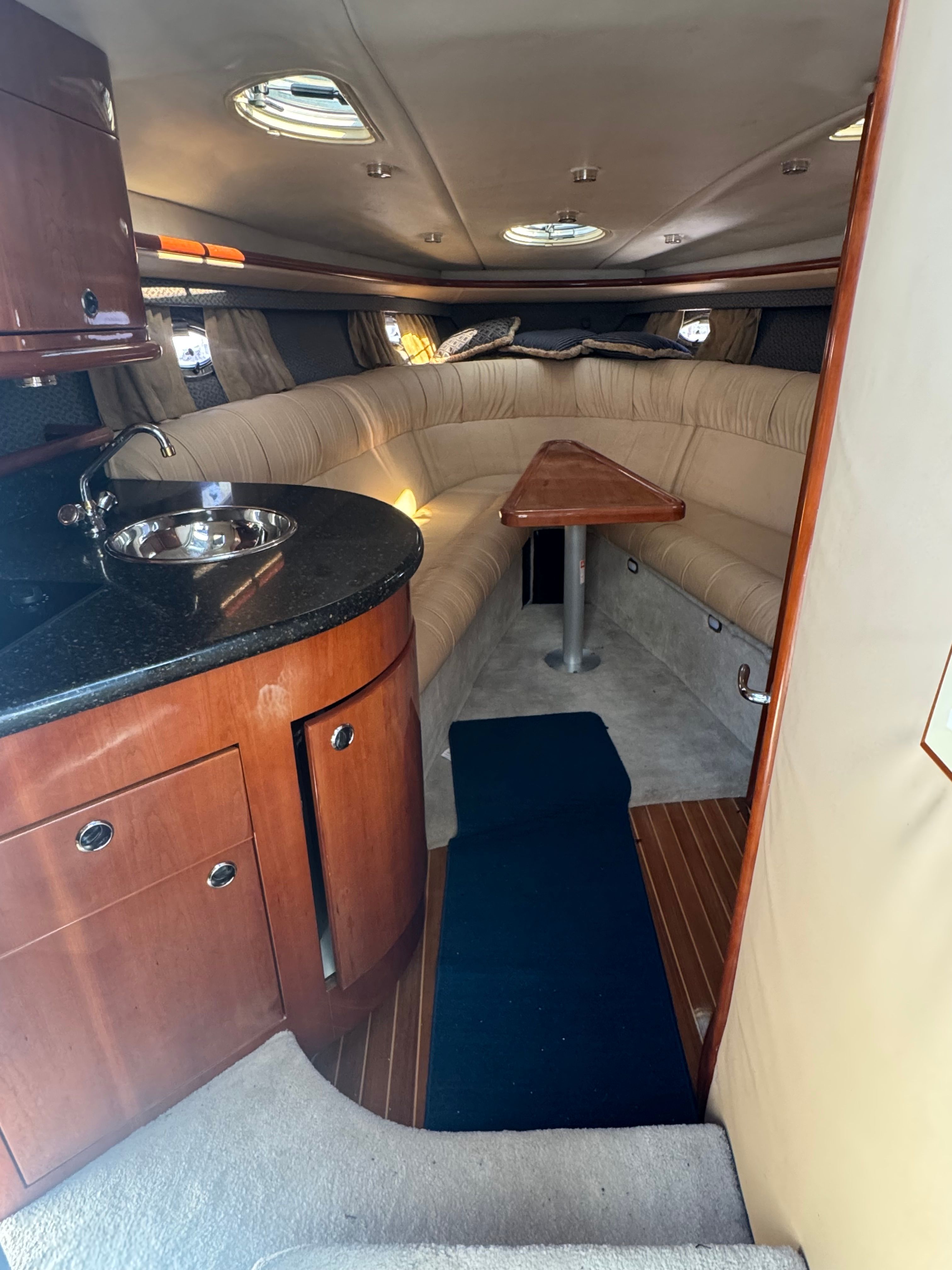 Interior of a 2003 Cobalt 360 with cushioned seating and a small kitchenette.