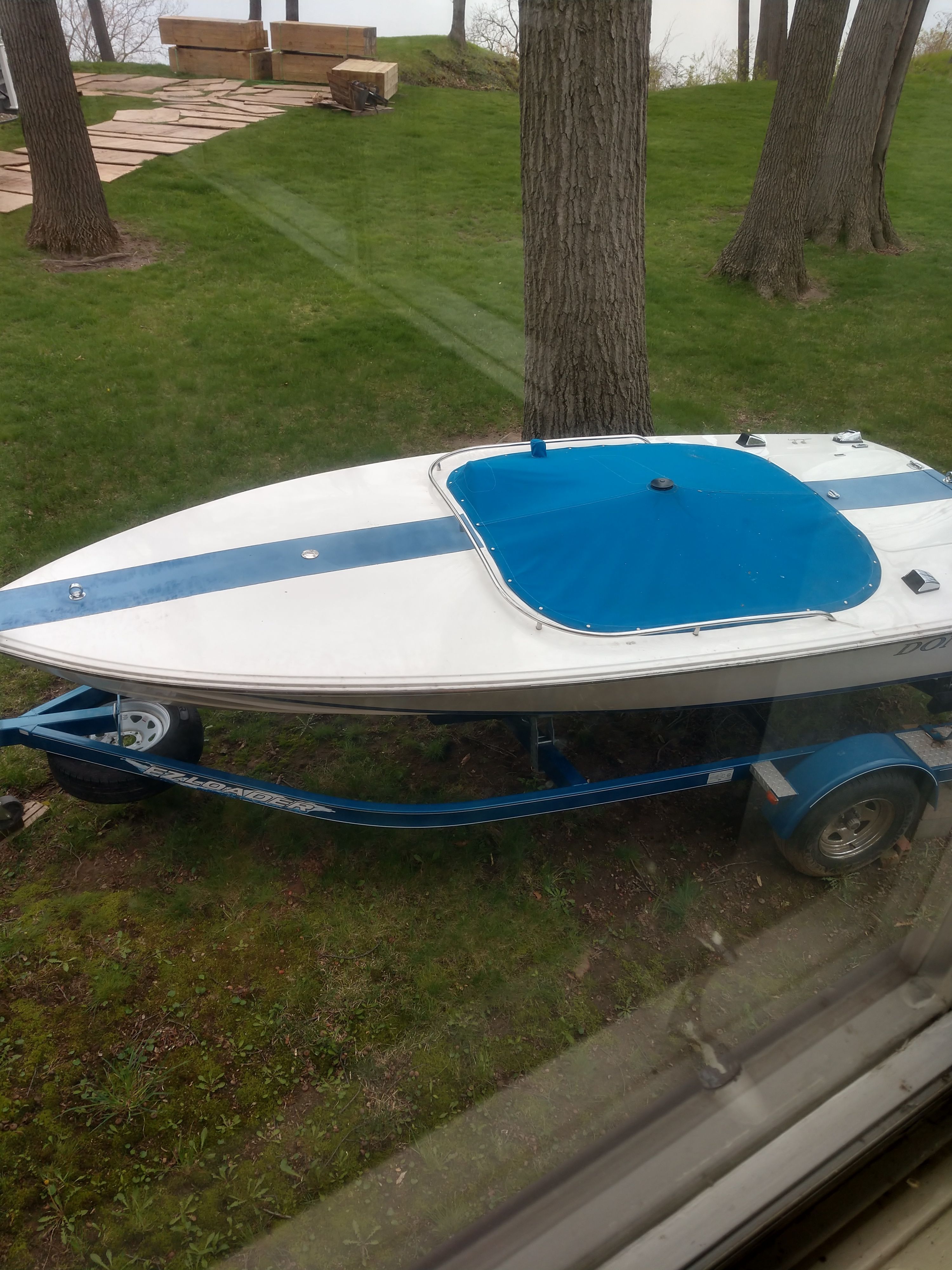 A 1997 Donzi Sweet Sixteen boat on a trailer, situated on a grassy area.