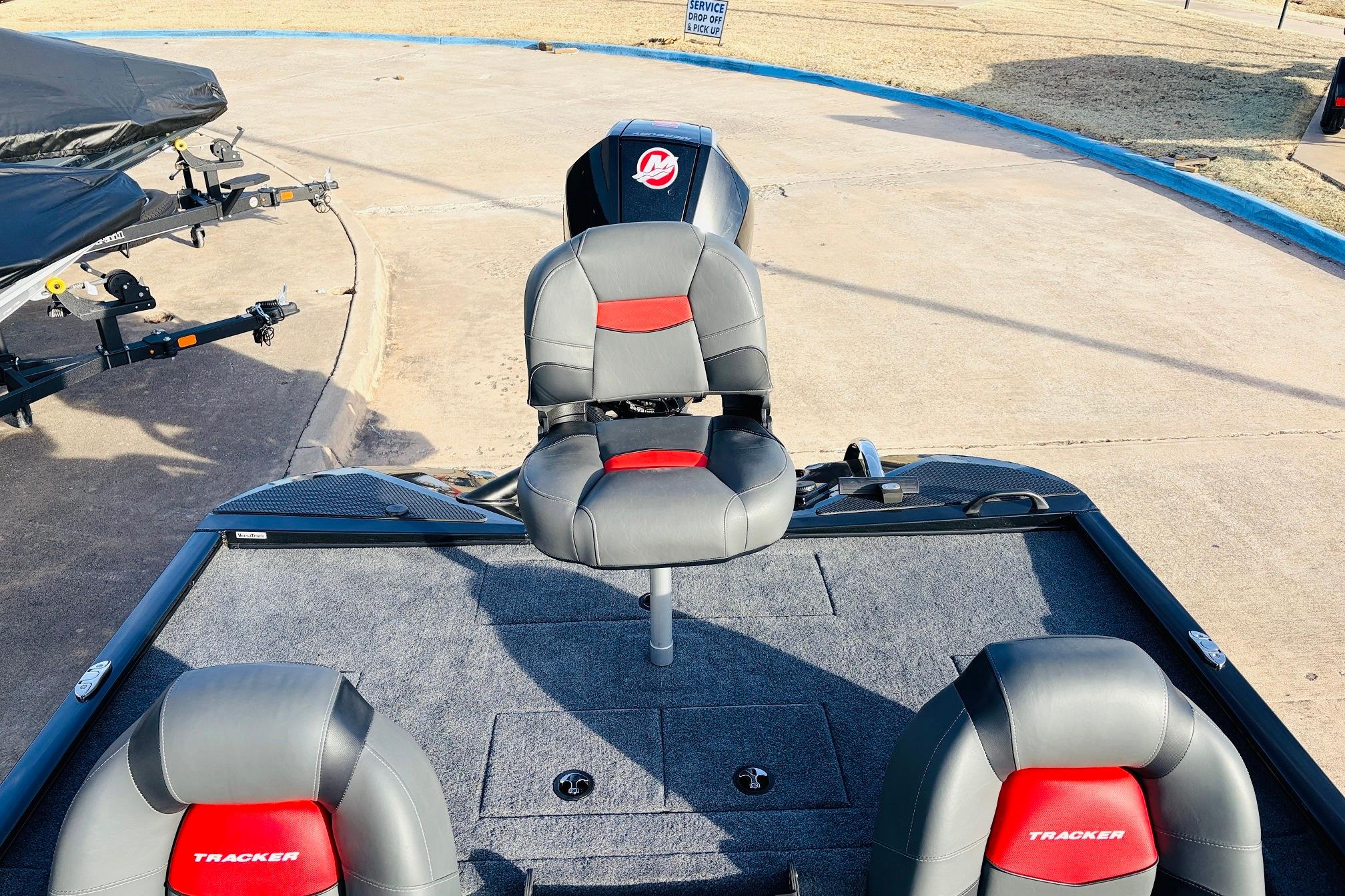 2025 Tracker Savage 215 boat interior with gray and red seating, parked on concrete.