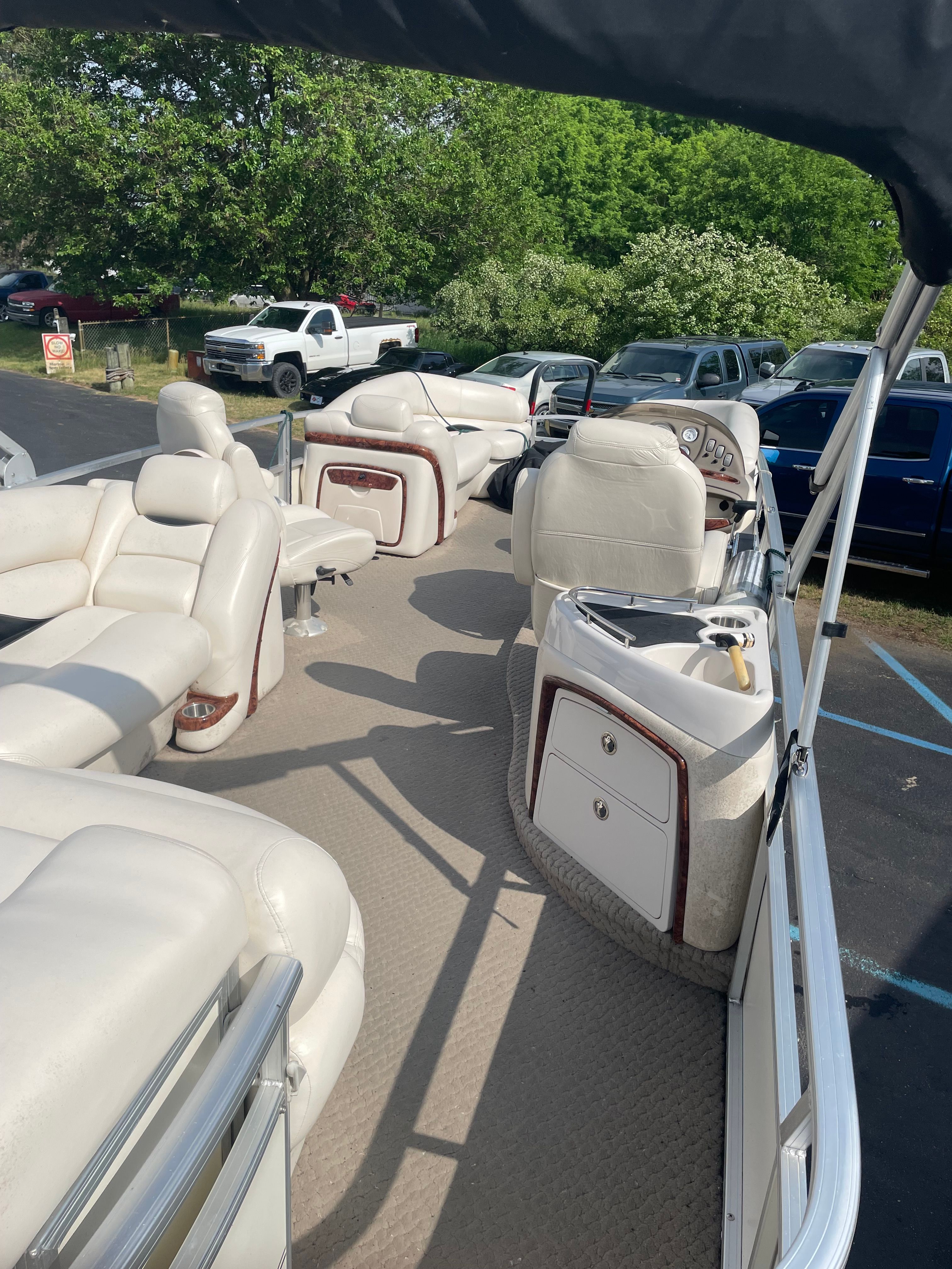 The image shows the interior of a party boat with white leather seats and a helm station.