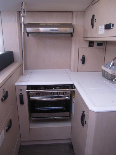 Modern kitchen in 2024 Jeanneau 60 yacht with stove and ample storage.
