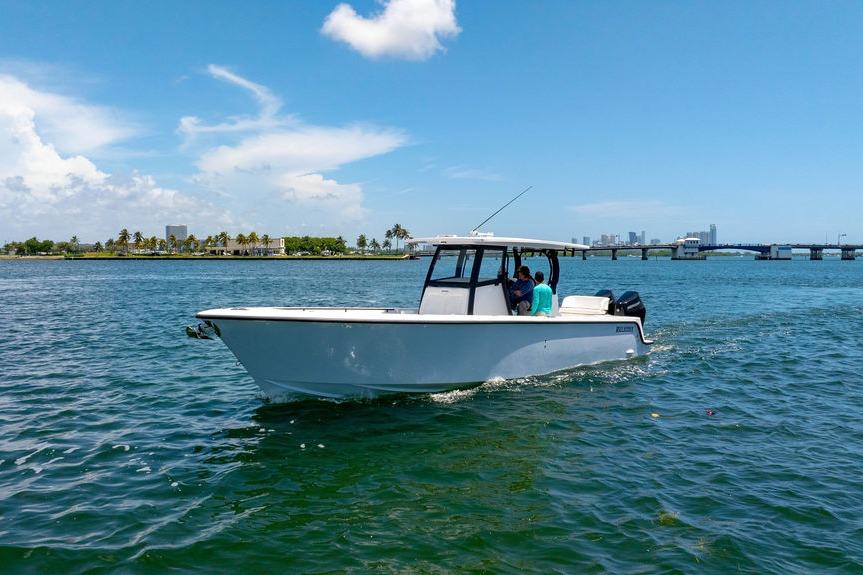 A 2027 Reef Runner 340 boat cruising on a sunny day near a city skyline.