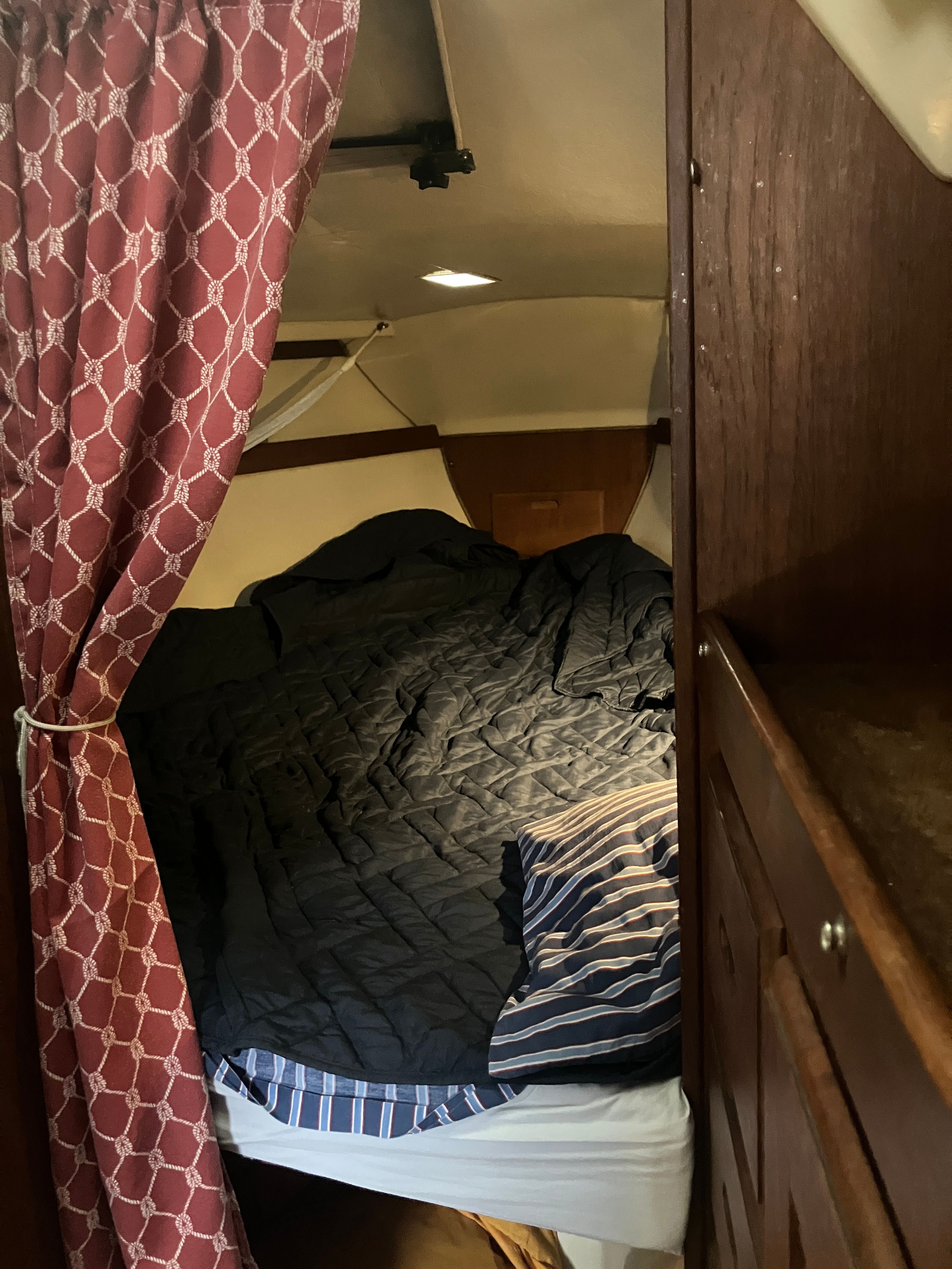 Cabin of a 1984 Catalina 30 with a cozy bed and curtain.