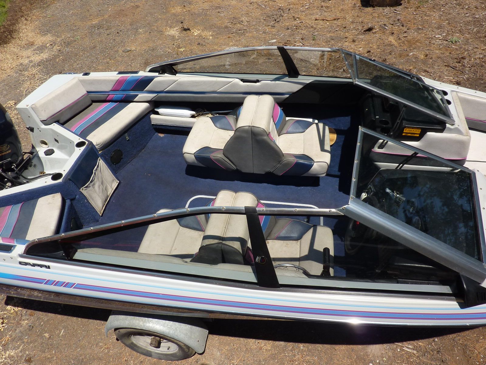 A 1989 Bayliner CAPRI with an open cockpit and blue upholstery on a trailer.