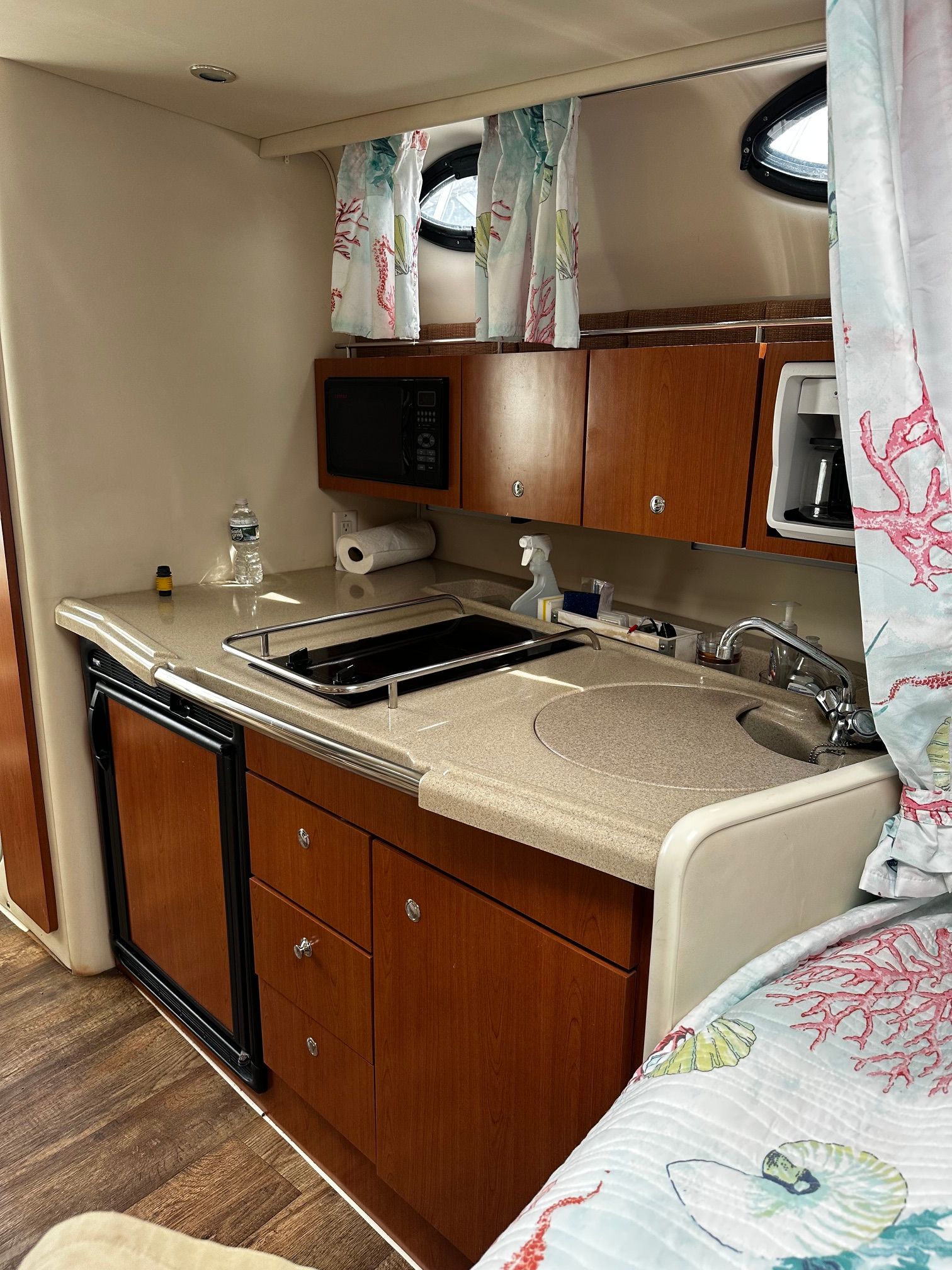 Interior view of a boat kitchen with wooden cabinets, sink, and microwave.