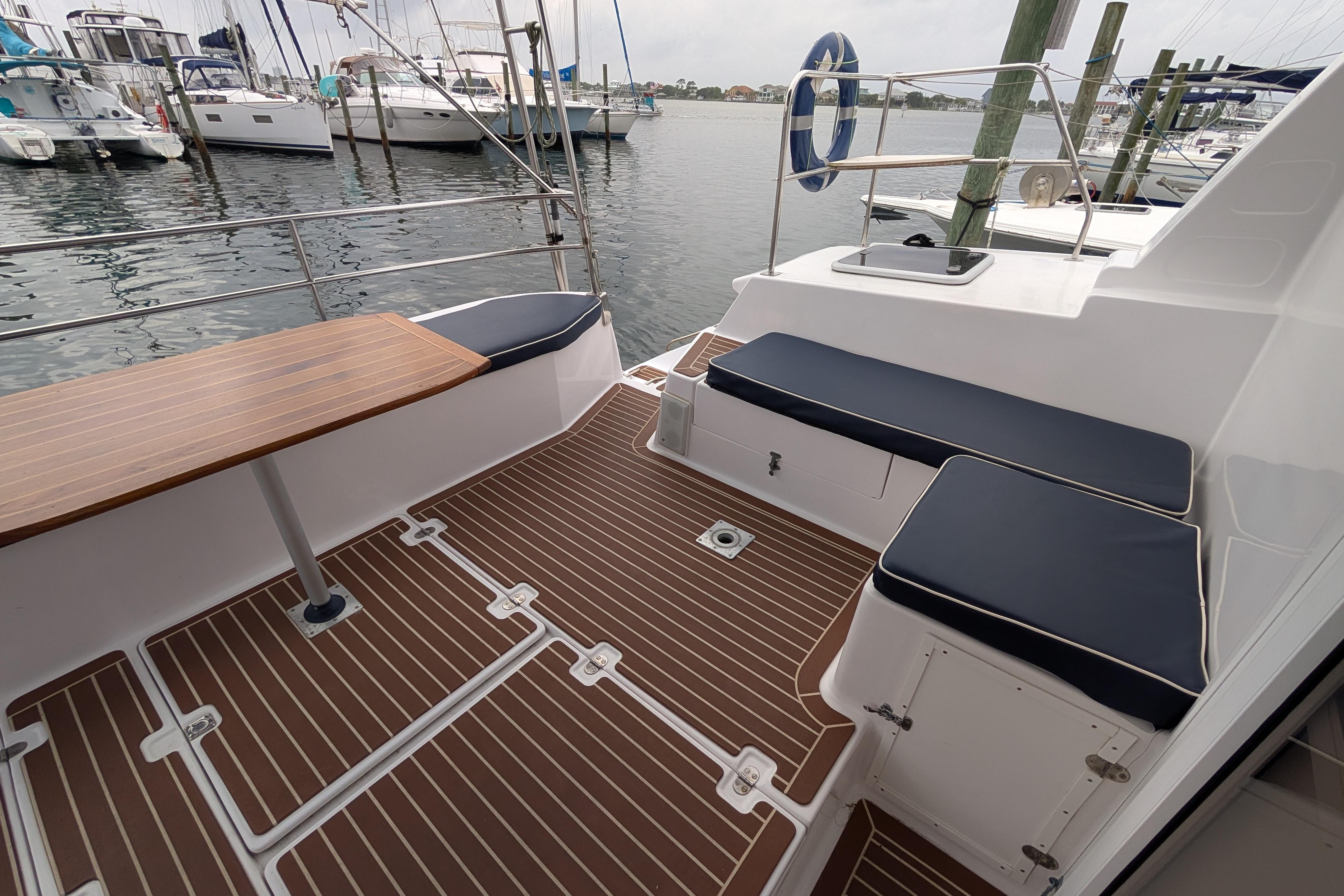 Island Spirit 37 catamaran deck, featuring seating and table, docked at marina, 1999 model.