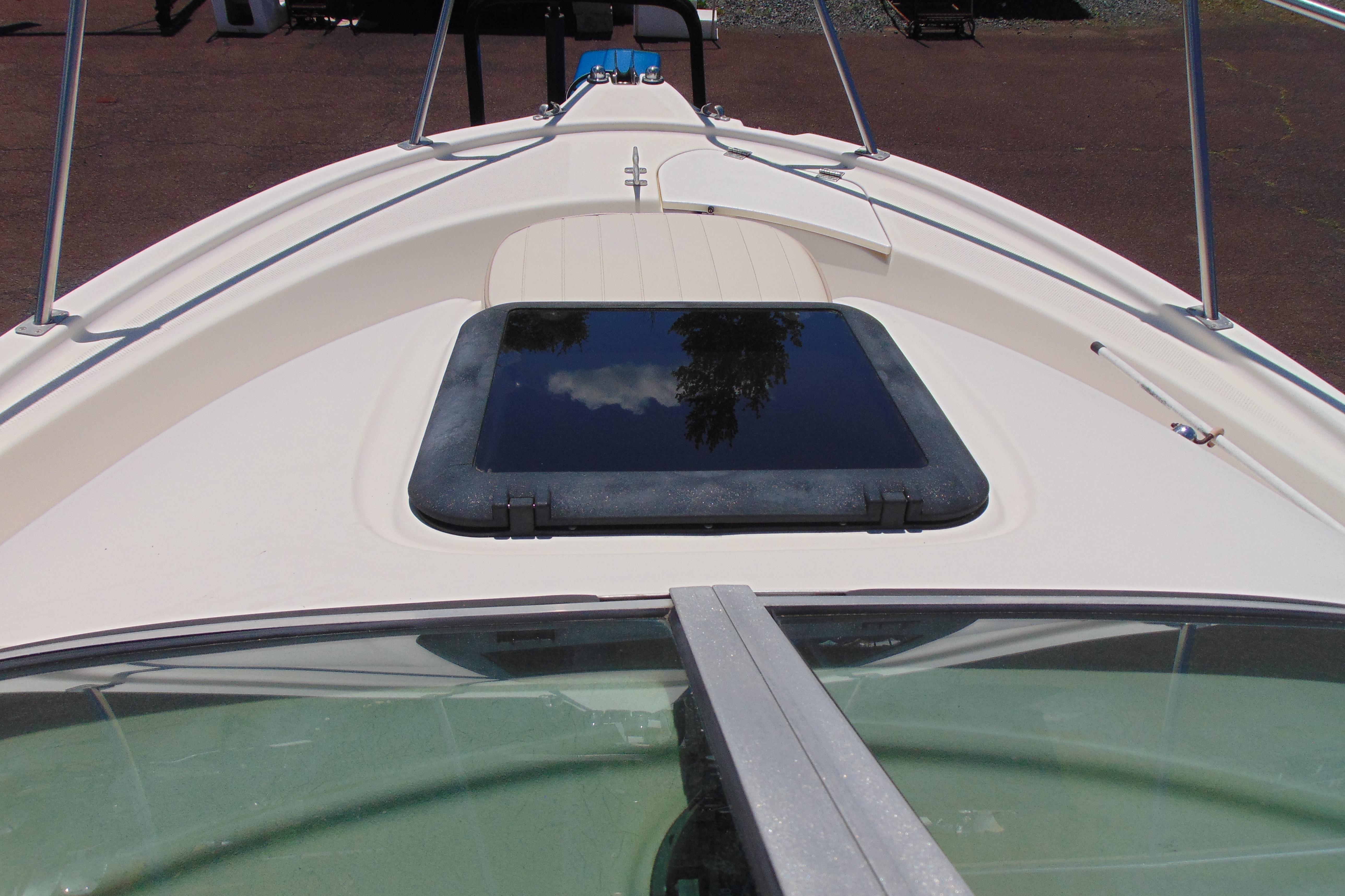 2002 Trophy Walkaround boat deck with hatch and railing, reflecting clear sky.