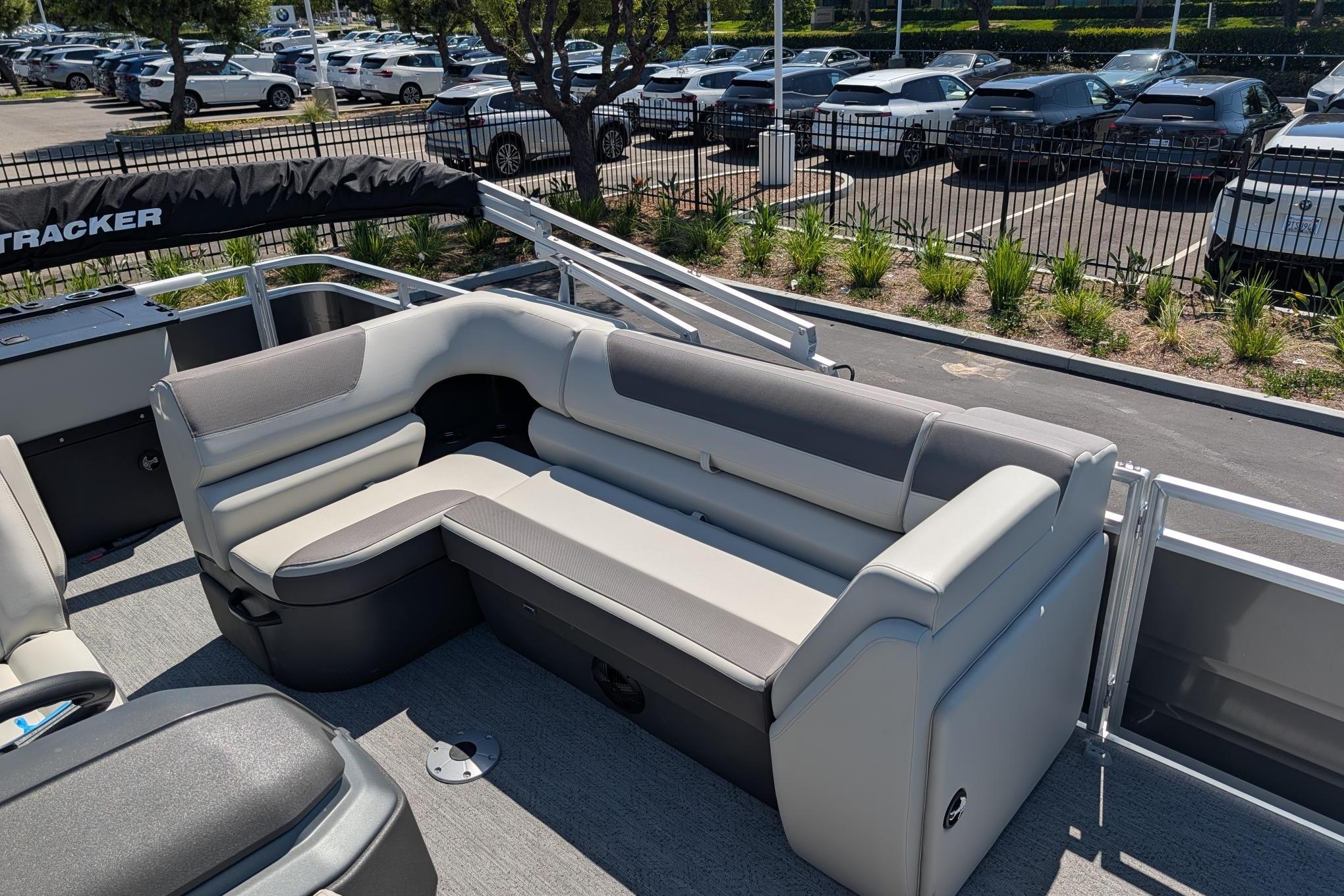 2026 Sun Tracker Fishin' Barge 22 DLX with comfortable seating in a parking lot setting.