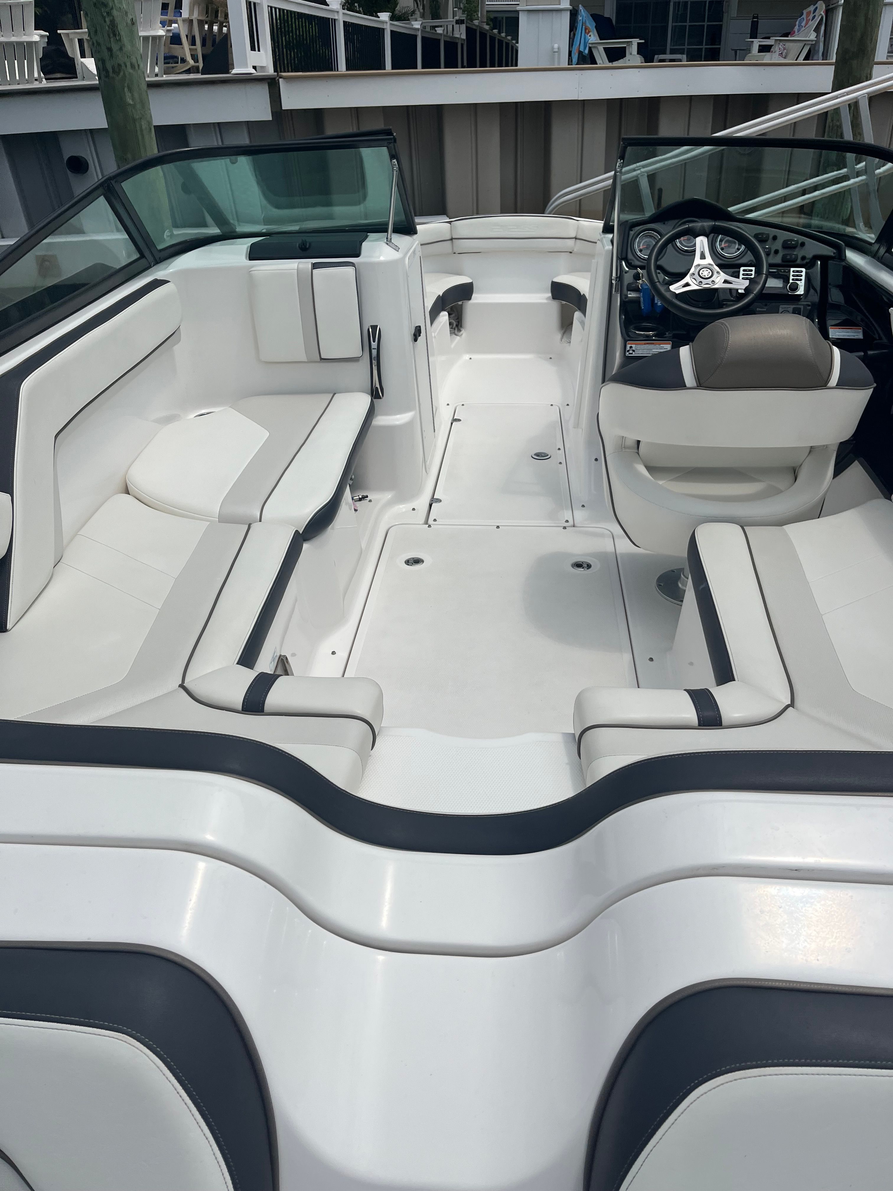 Interior view of a modern boat with white seating and a black steering wheel.