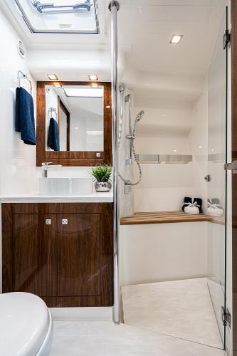 Luxurious bathroom in 2021 Riviera 5400 Sport Yacht with modern fixtures and wooden accents.