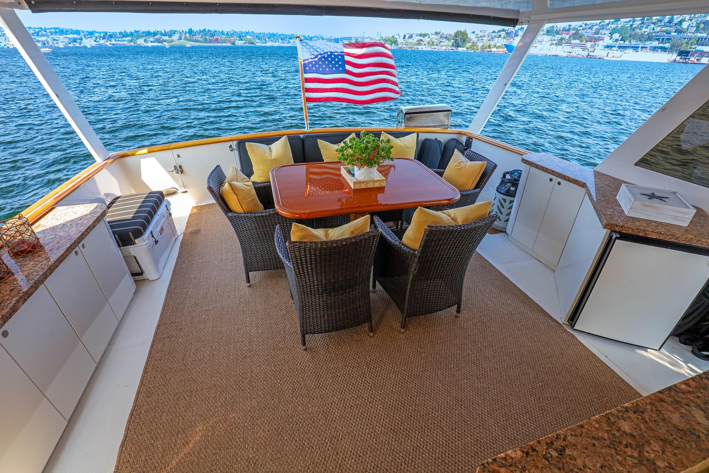Luxurious 1987 Ocean Alexander 480 Sport Sedan yacht deck with dining area and American flag.