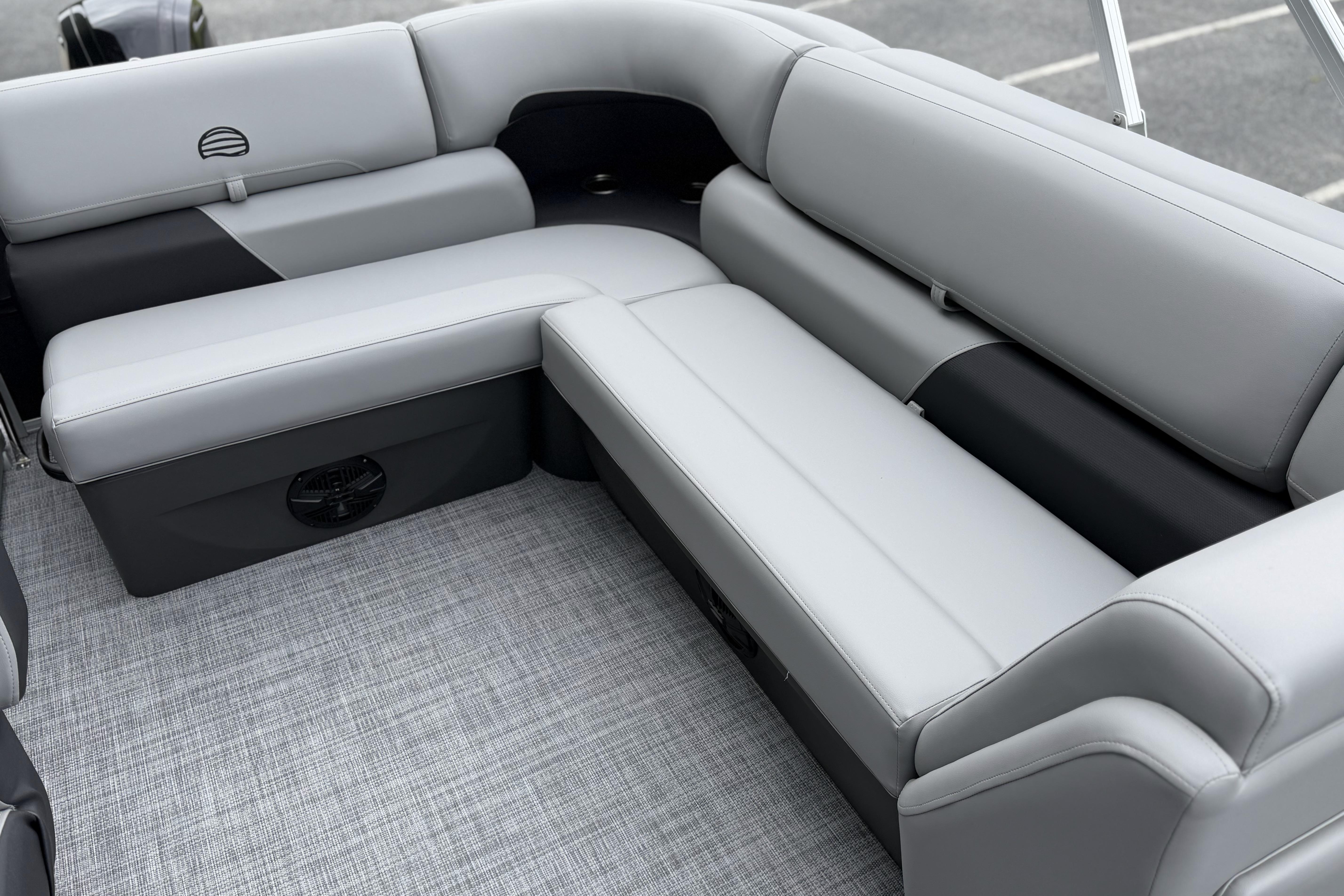 2026 Sun Tracker Party Barge 20 DLX interior with gray cushioned seating and speaker system.
