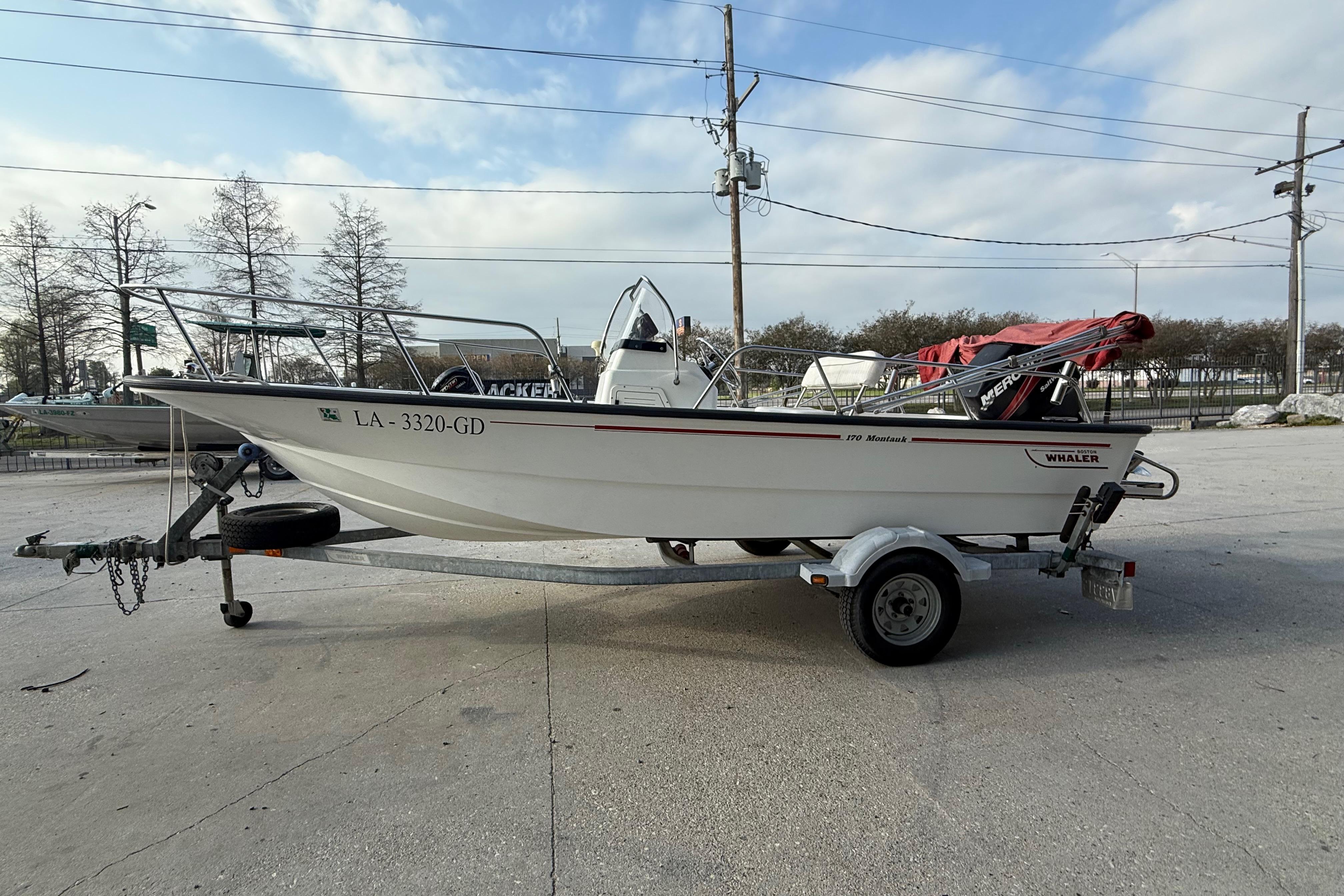 2005 Boston Whaler 17 Montauk boat on trailer, parked outdoors under a cloudy sky.