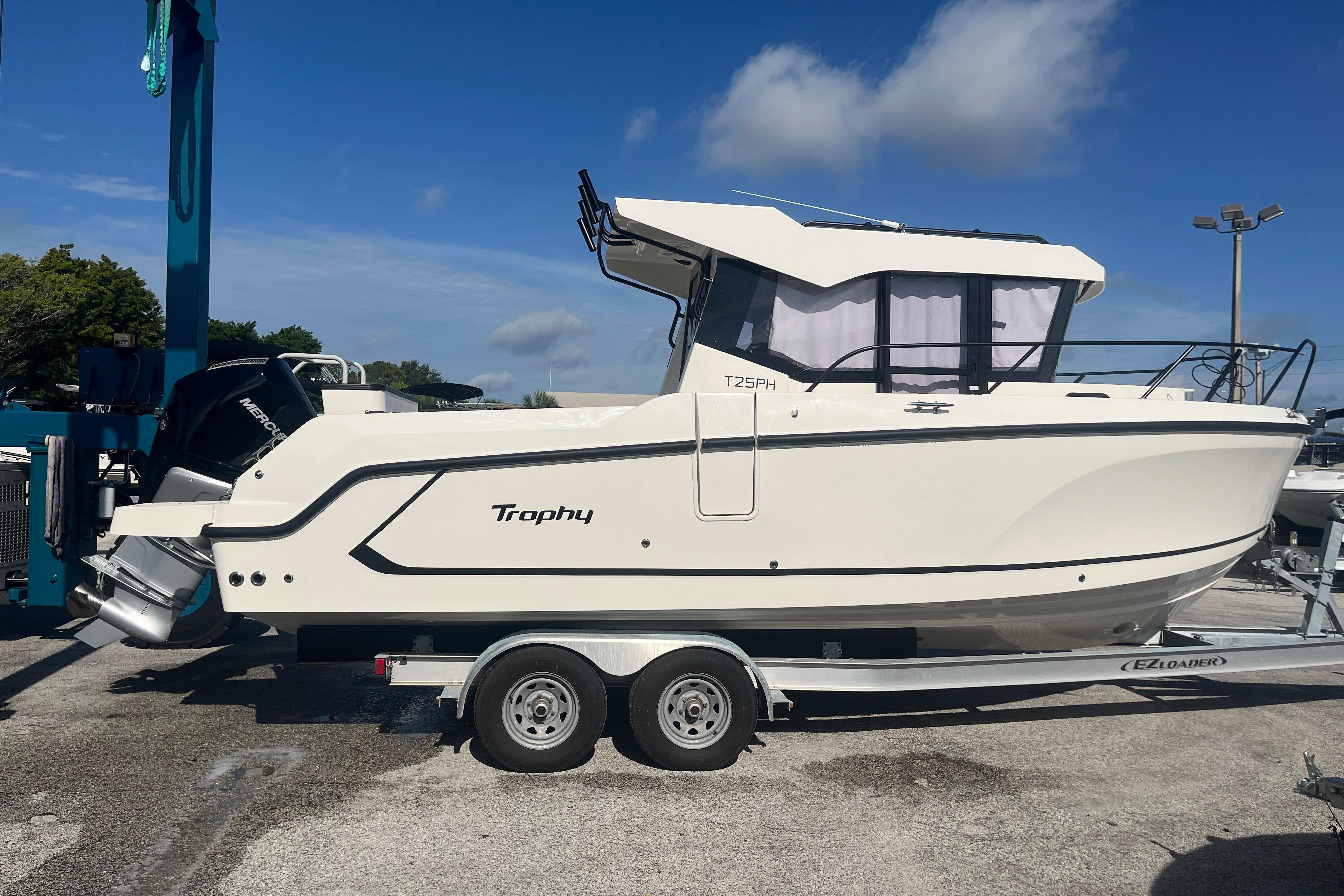 2025 Bayliner Trophy T25 Pilothouse boat on trailer under clear blue sky.
