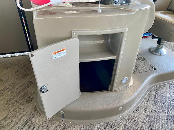 An open storage compartment on a boat with carpeted flooring and a seat nearby.