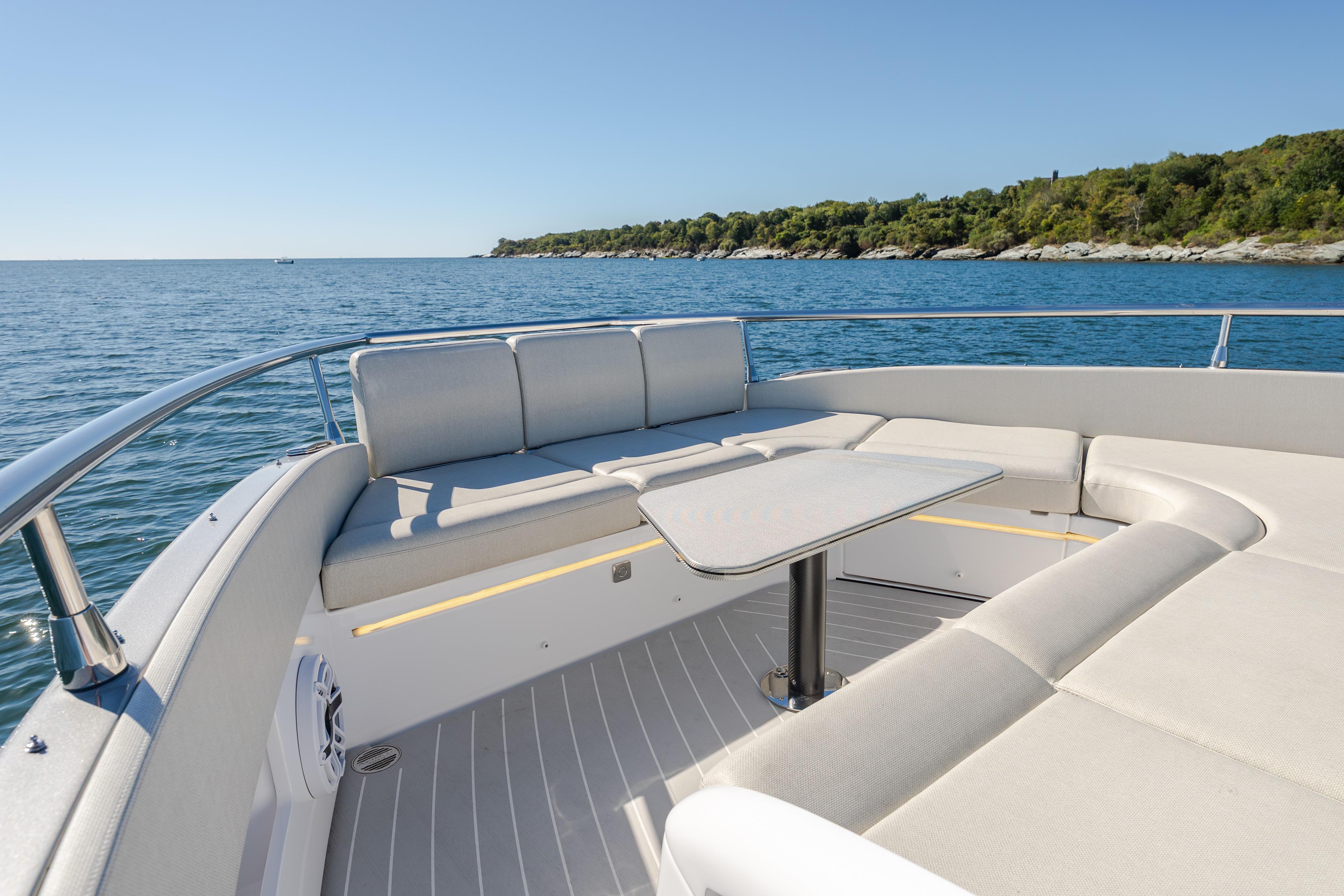 2023 Azimut Verve 47 yacht deck with seating and table, overlooking serene ocean and coastline.