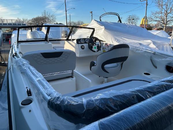 2024 Bayliner Element M19 boat interior with steering wheel and seating, wrapped in protective plastic.